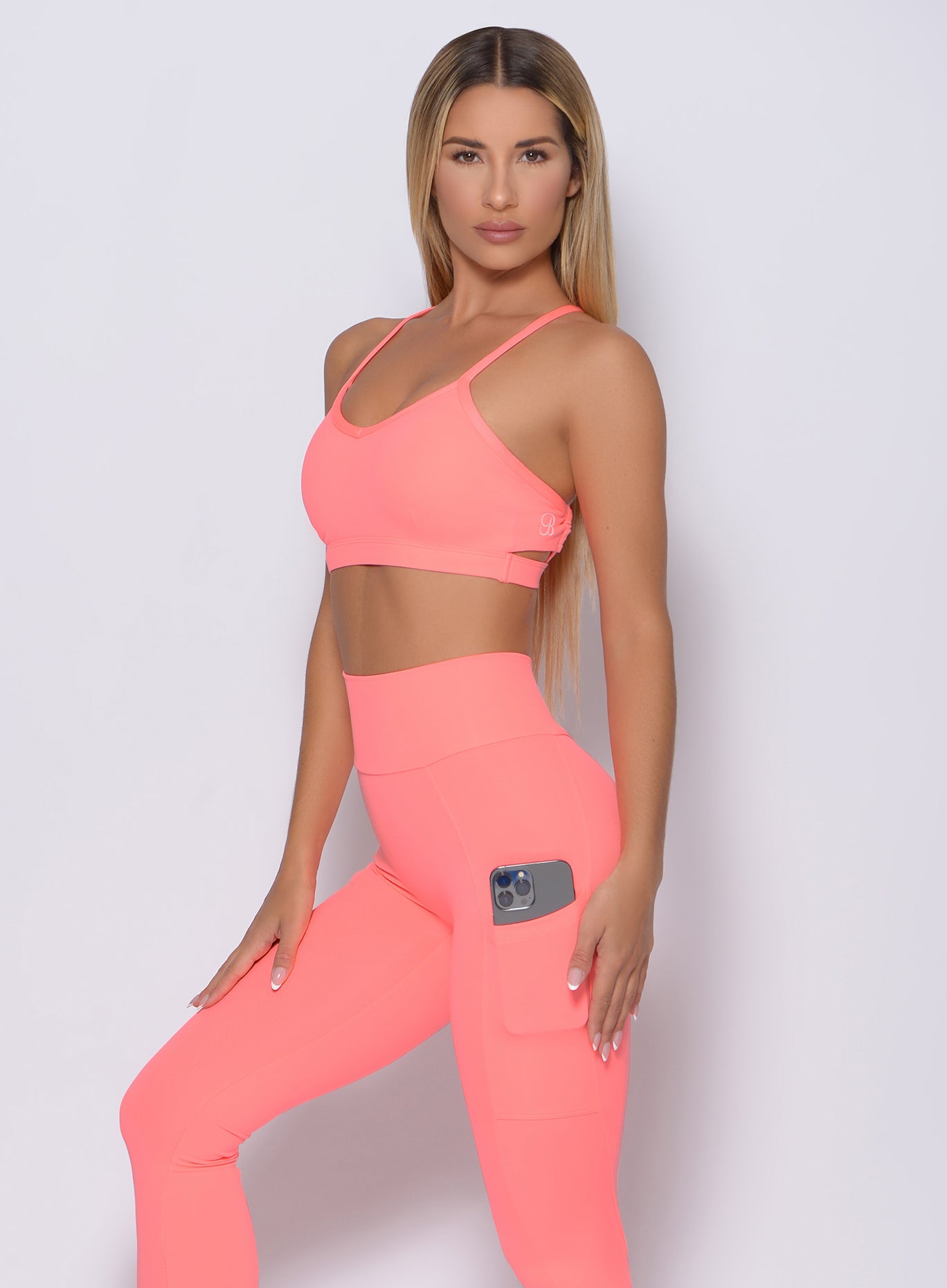 Left side view of the model wearing our pumped sports bra in wild peach color and a matching leggings
