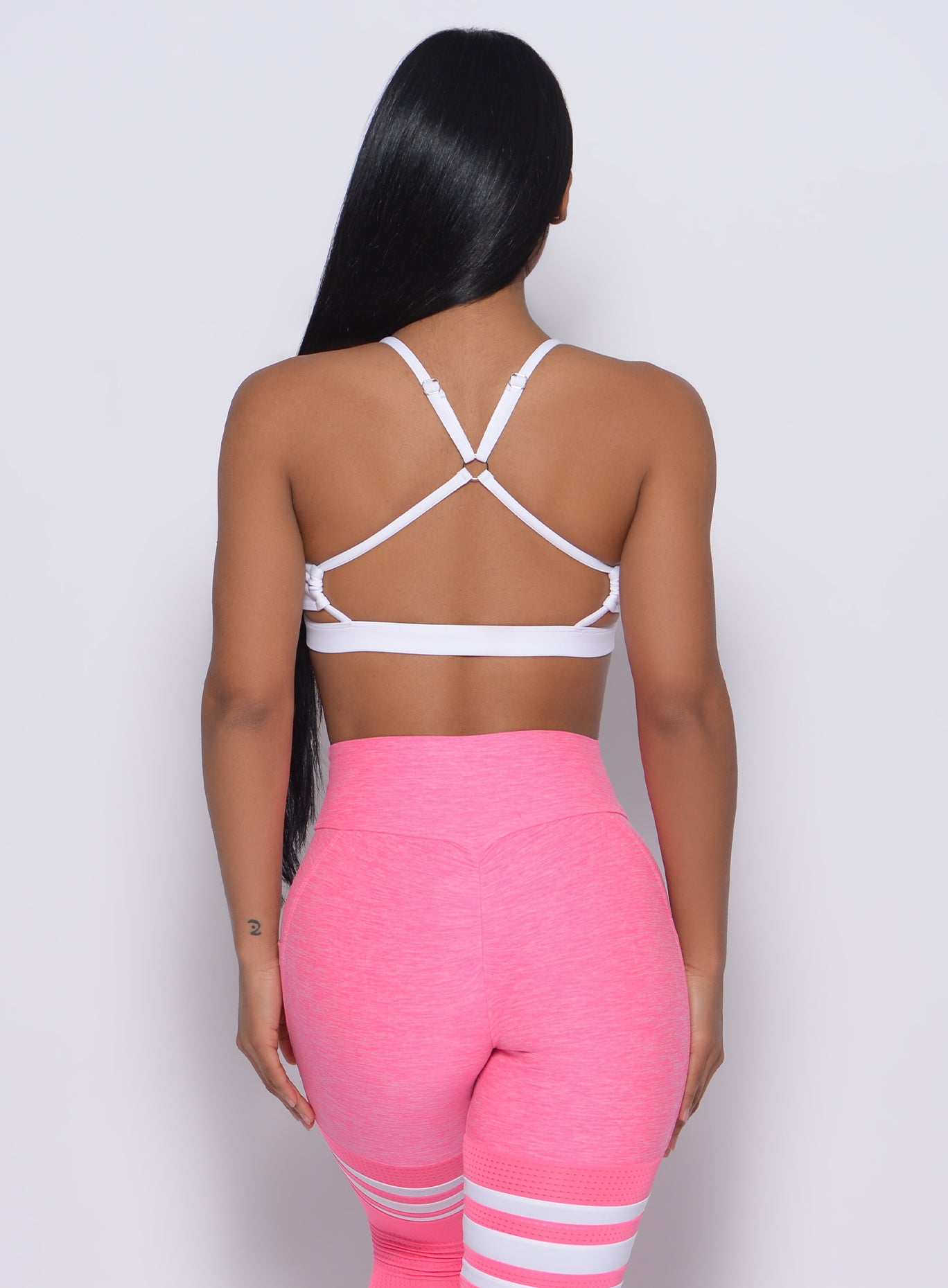 White Pumped Sports Bra with strappy open back and supportive high-waisted striped leggings.