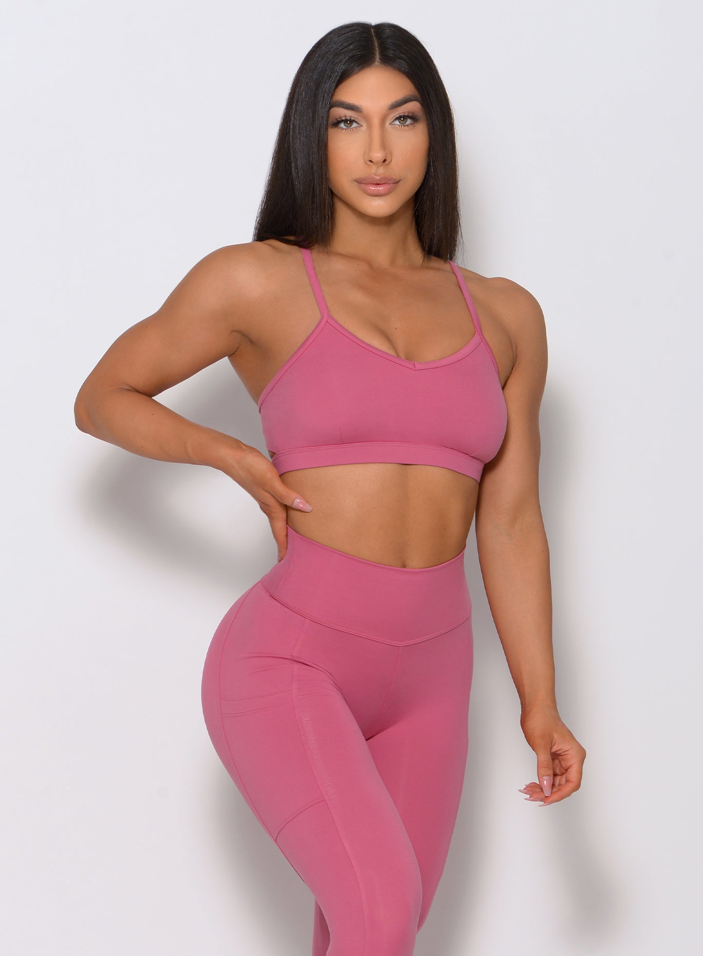 model facing forward with her right hand on waist wearing our pumped sports bra in blush color and a matching high waist leggings