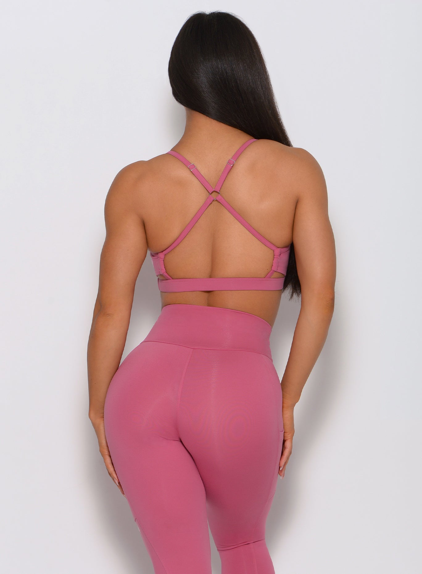 Back view of the model wearing our pumped sports bra in blush color and a matching high waist leggings