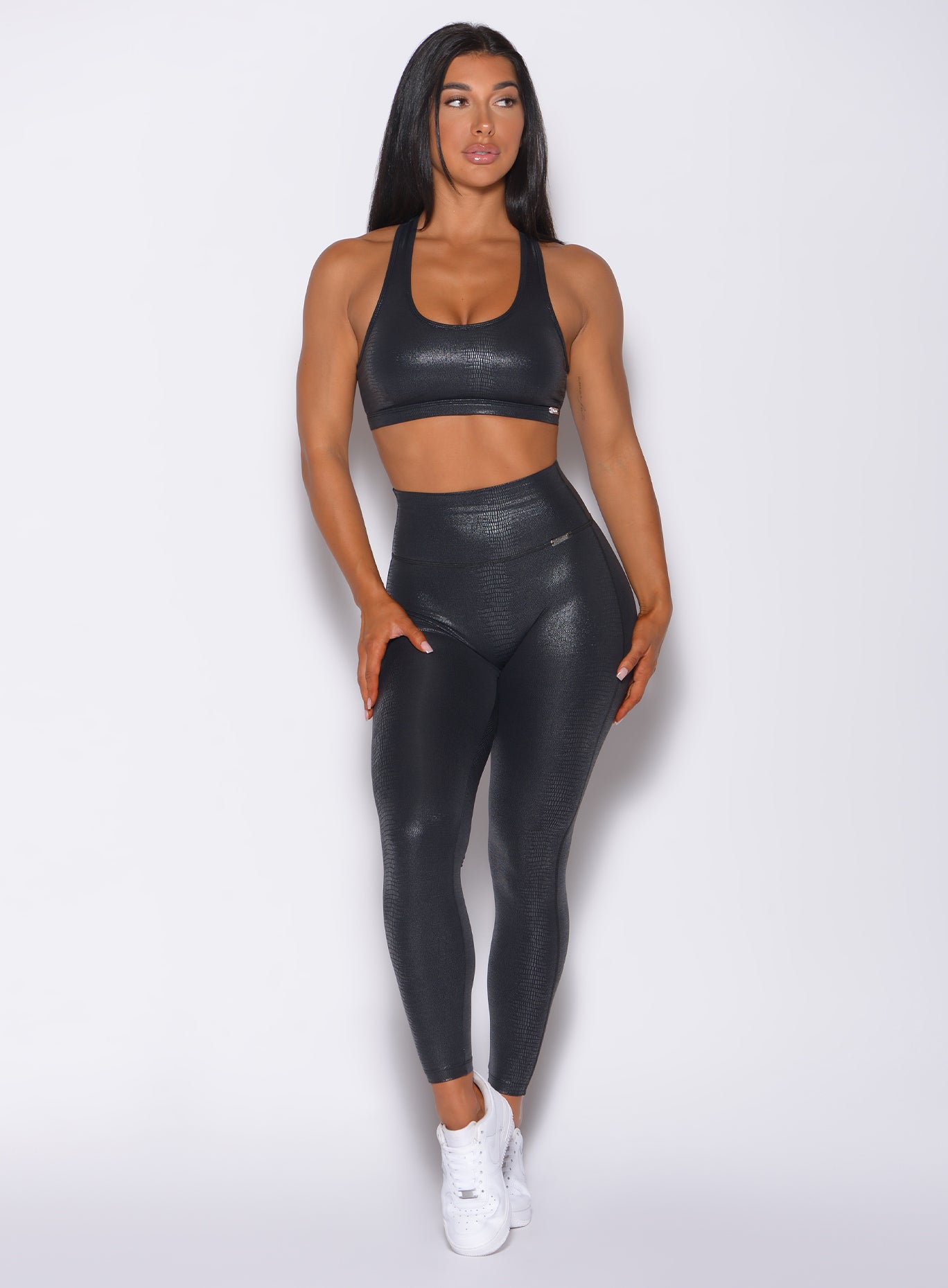 Front profile view of a model wearing our shine leggings in black python color and a matching sports bra