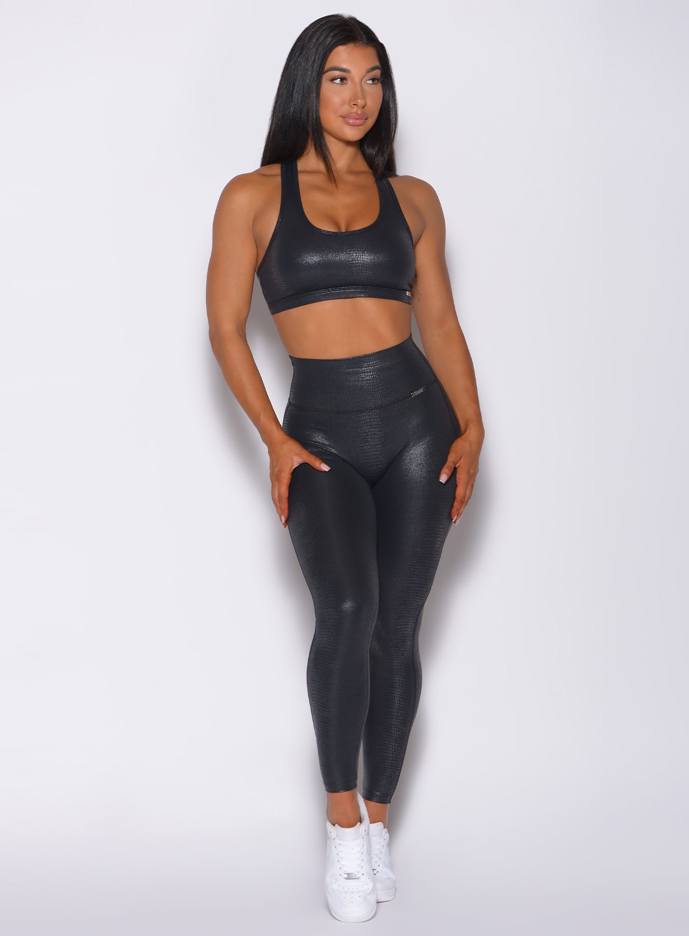 Front profile view of a model in our shine leggings in black python color and a matching bra 