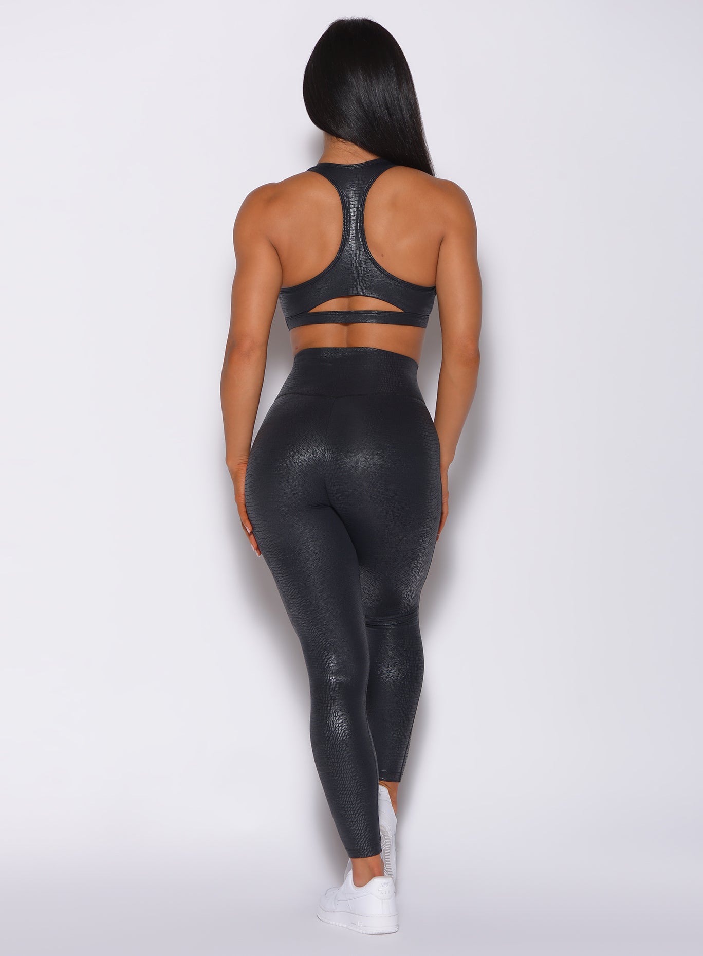 Back profile view of a model in our shine leggings in black python color and a matching bra