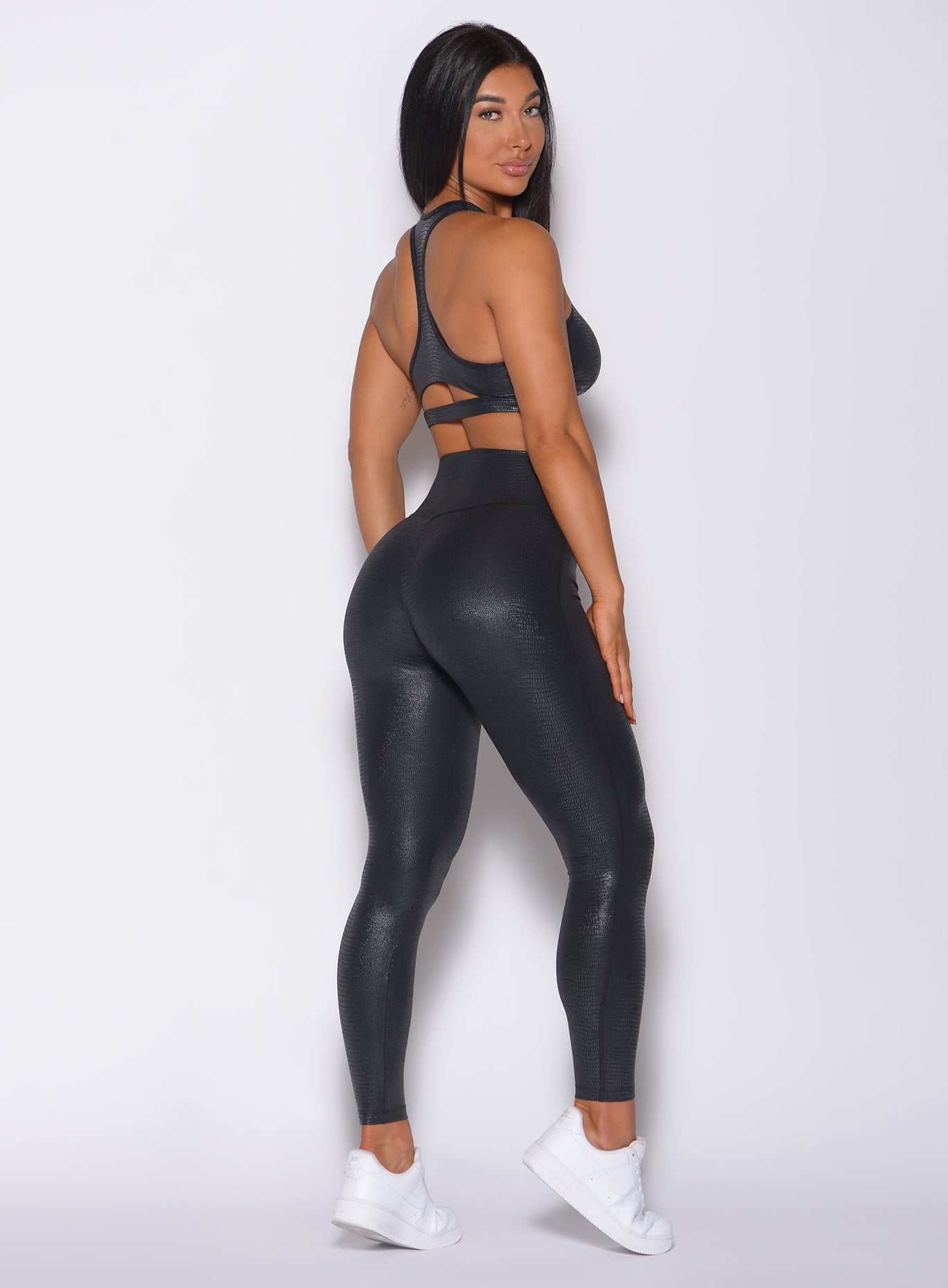 Right side profile view of a model in our shine leggings in black python color and a matching bra