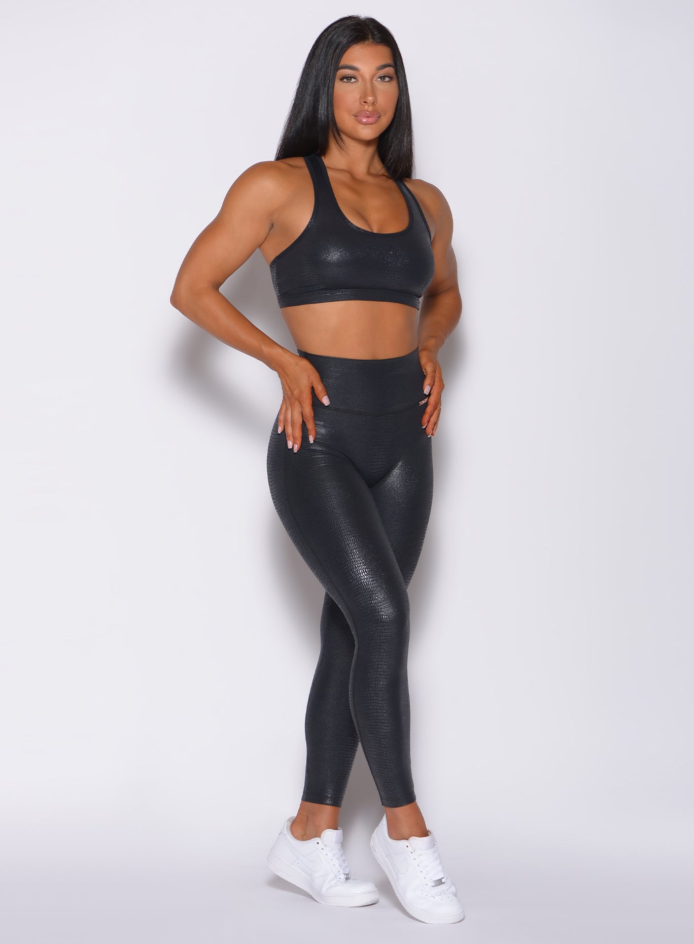 Front profile view of a model angled right wearing our shine leggings in black python color 