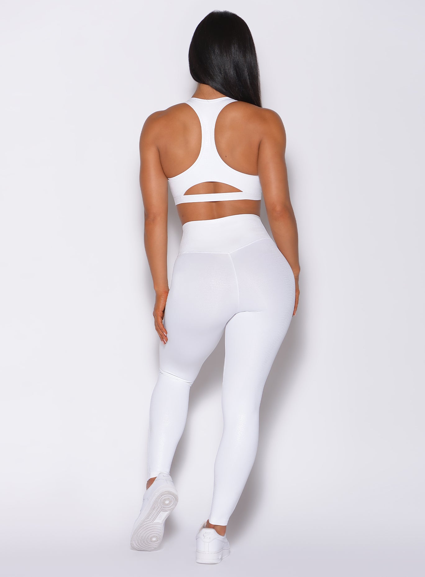 Back profile view of a model in our shine leggings in white python color and a matching bra