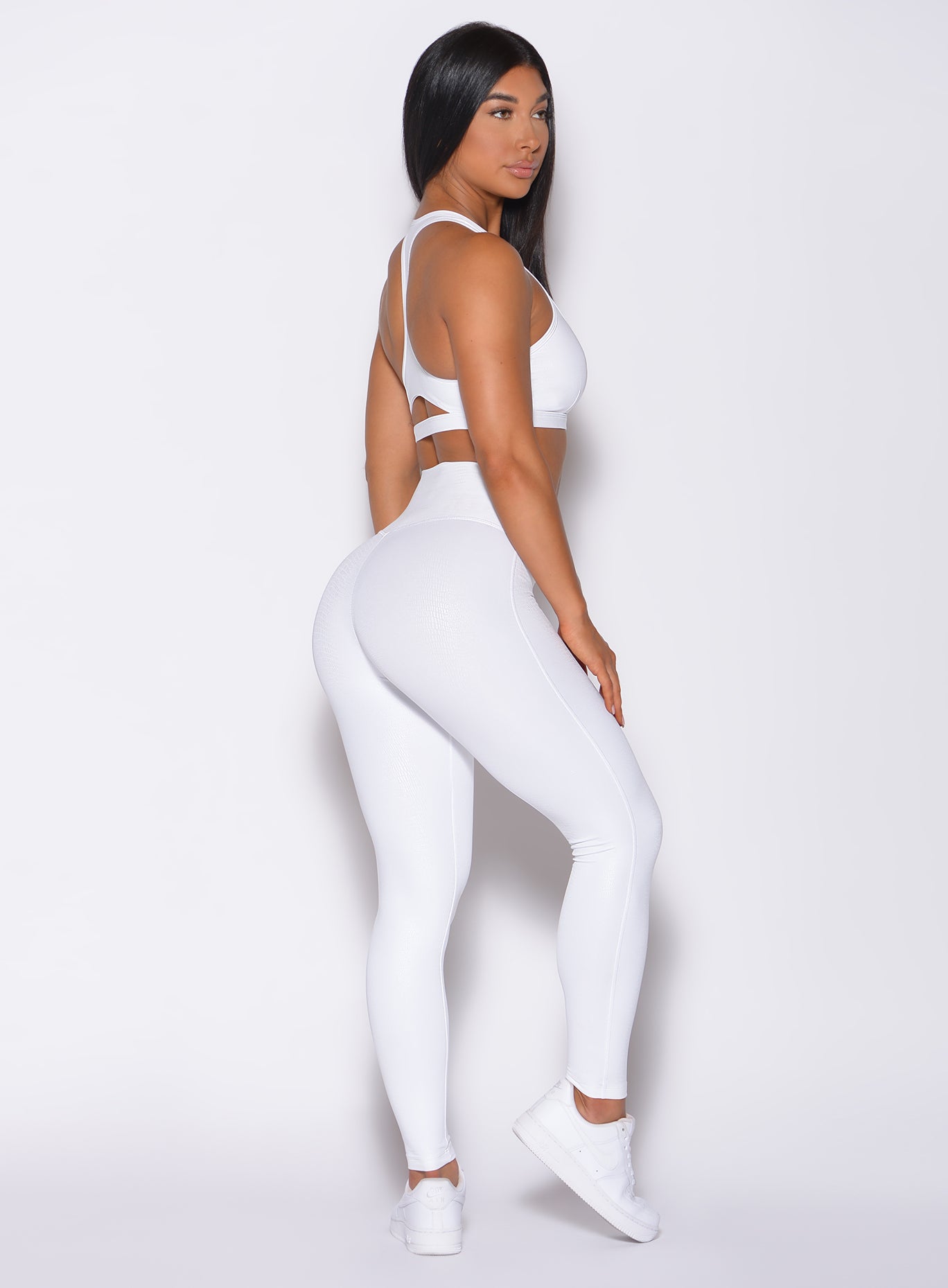 Right side profile view of a model wearing our shine leggings in white python color and a matching bra