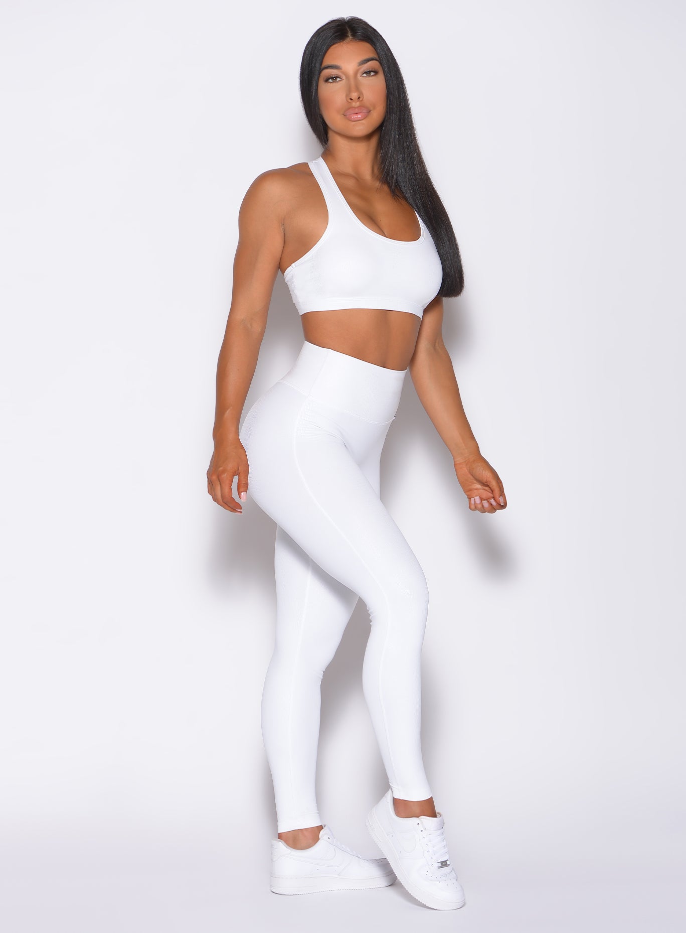 Right side profile view of a model angled right wearing our shine leggings in white python color and a matching bra