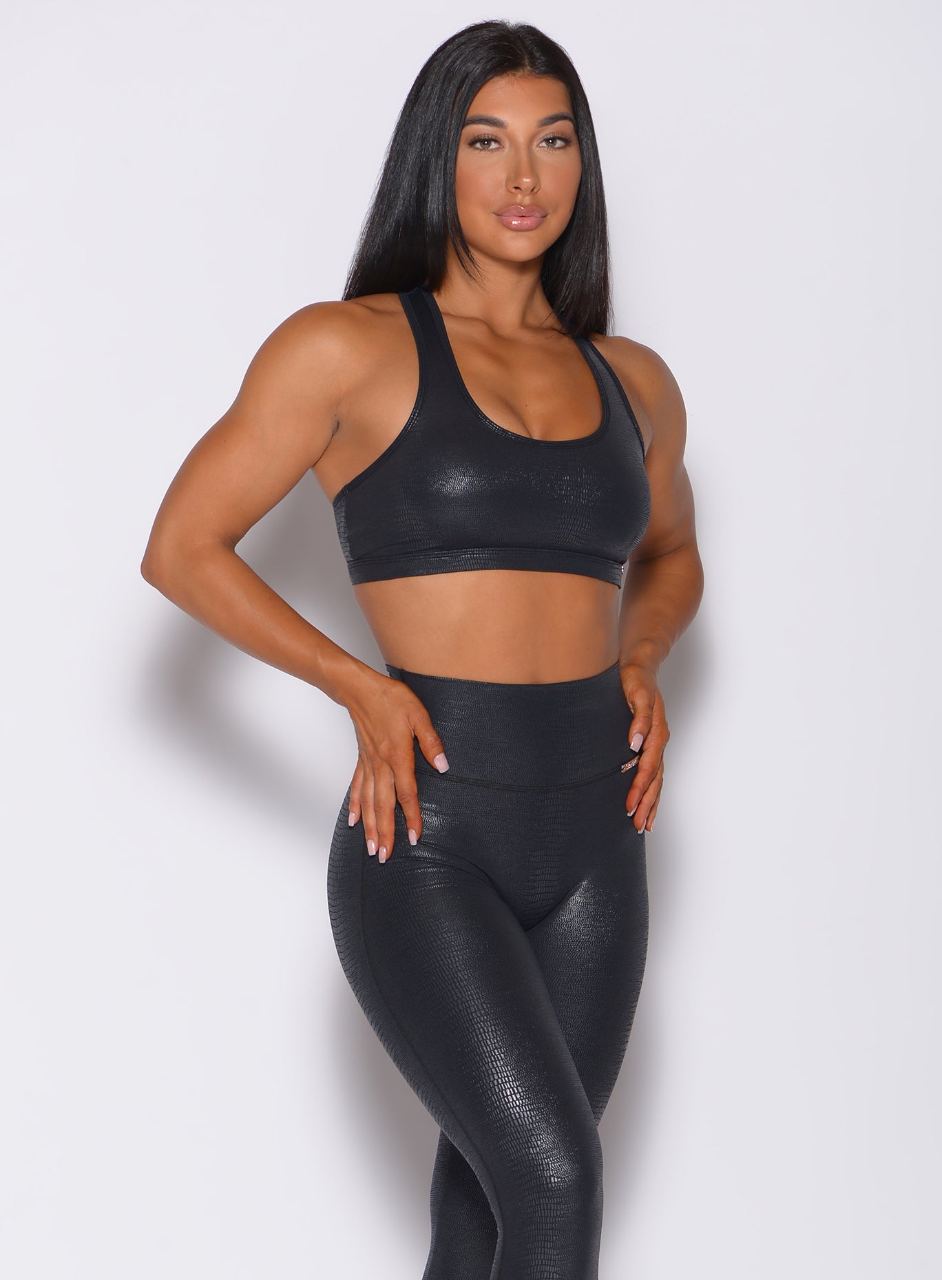 Right side profile view of a model angled right wearing our shine sports bra in black python color and a matching black leggings