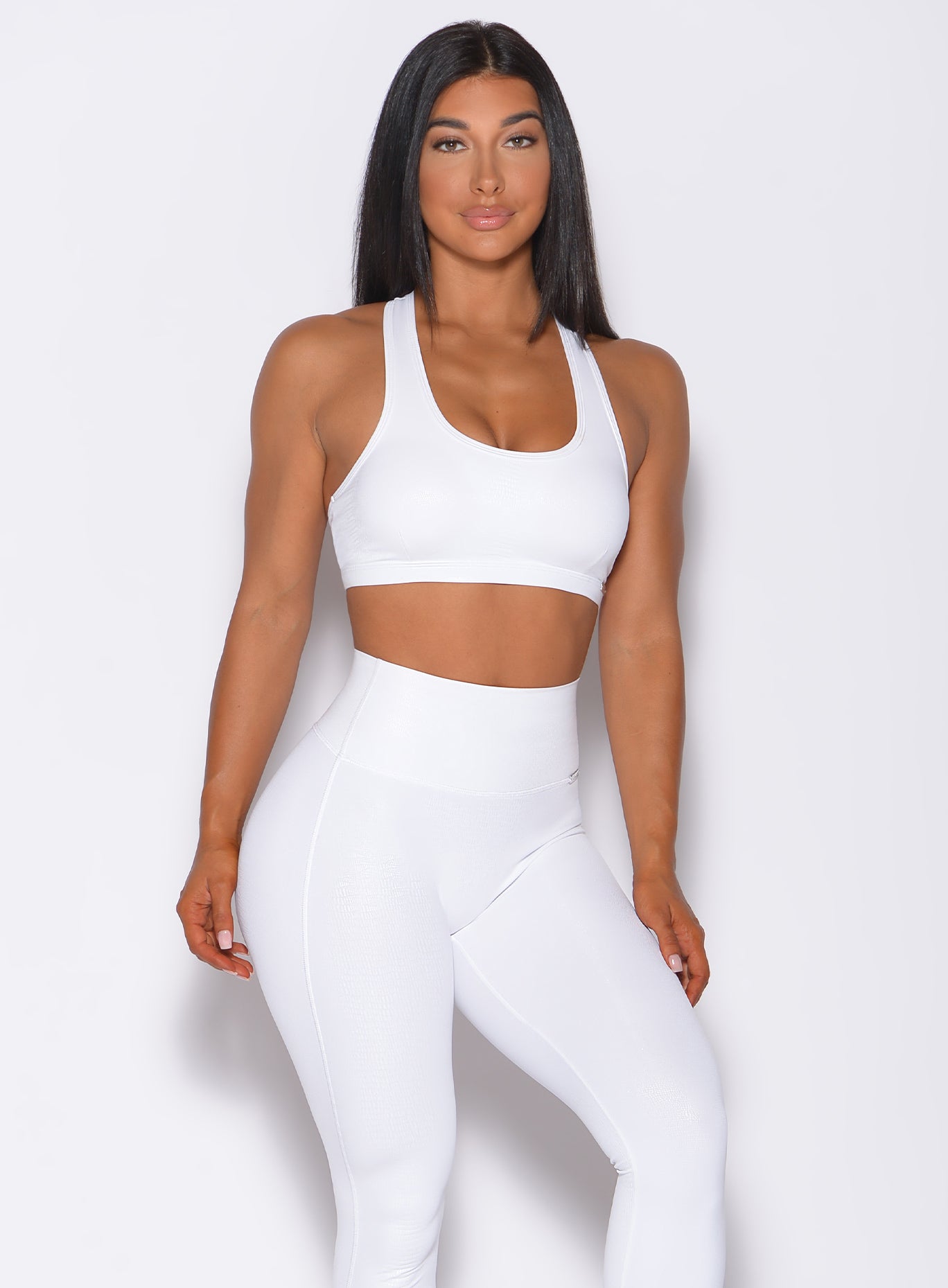 Front profile view of a model facing forward wearing our shine sports bra in white python color and a matching leggings