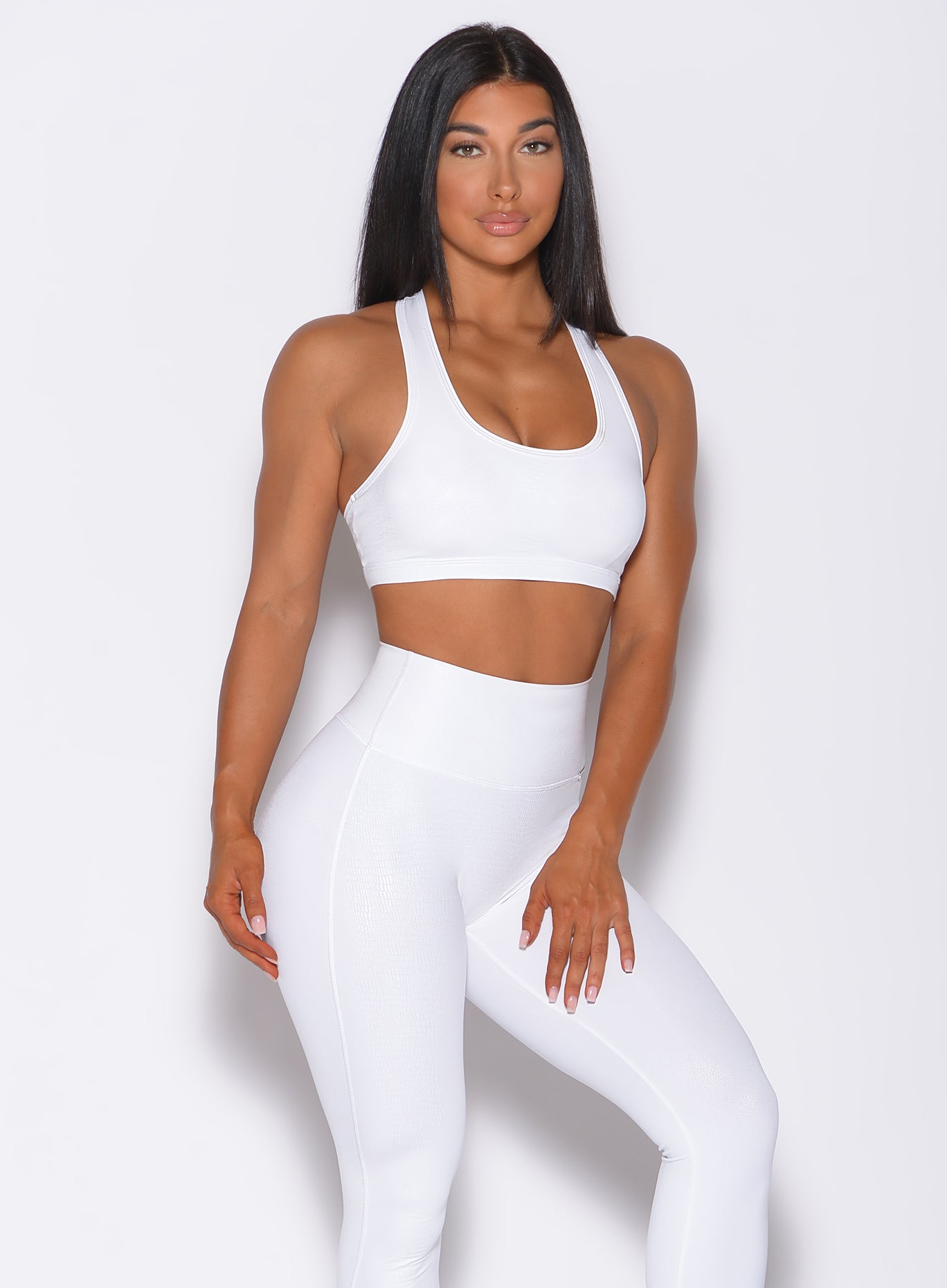 Model facing forward wearing our shine sports bra in white python color and a matching leggings 