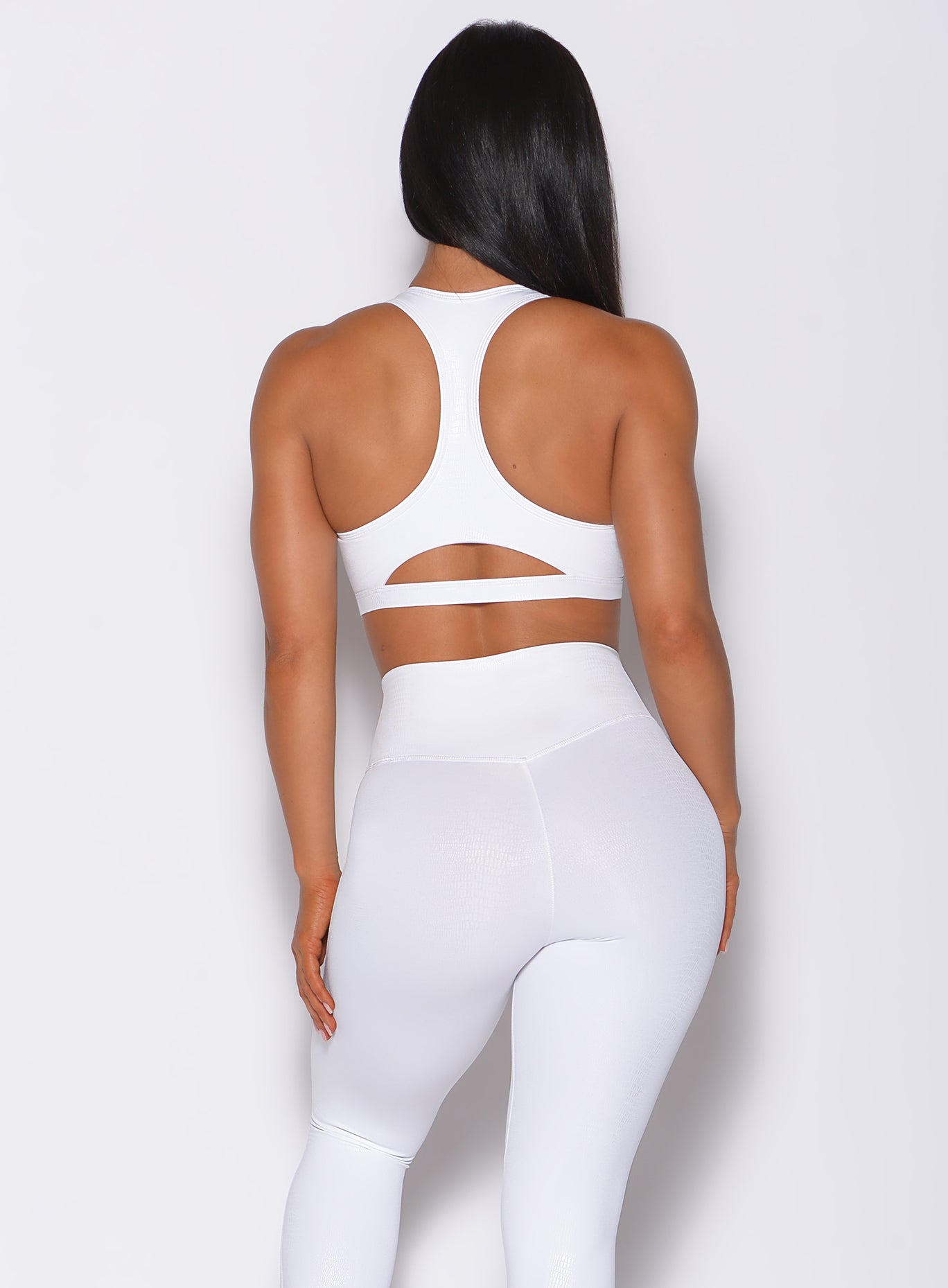 Back profile view of a model in our shine sports bra in white python color and a matching leggings