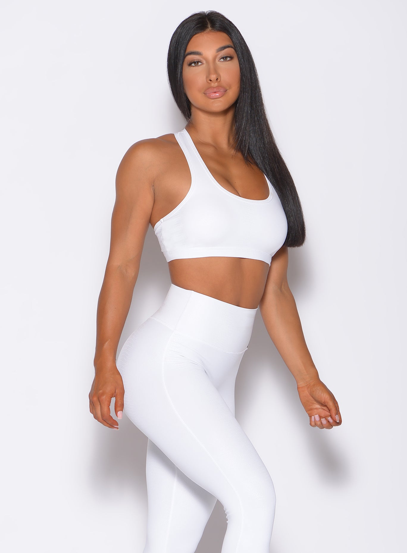 Right side profile view of a model angled right wearing our shine sports bra in white python color and a matching leggings