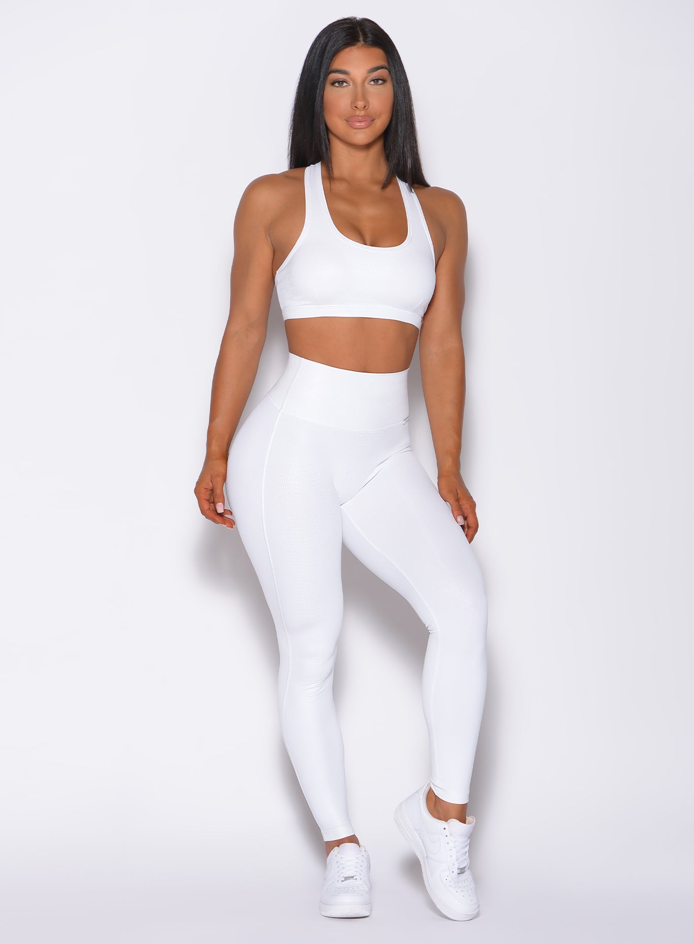 Front profile picture of a model in our shine sports bra in white python color and a matching leggings 