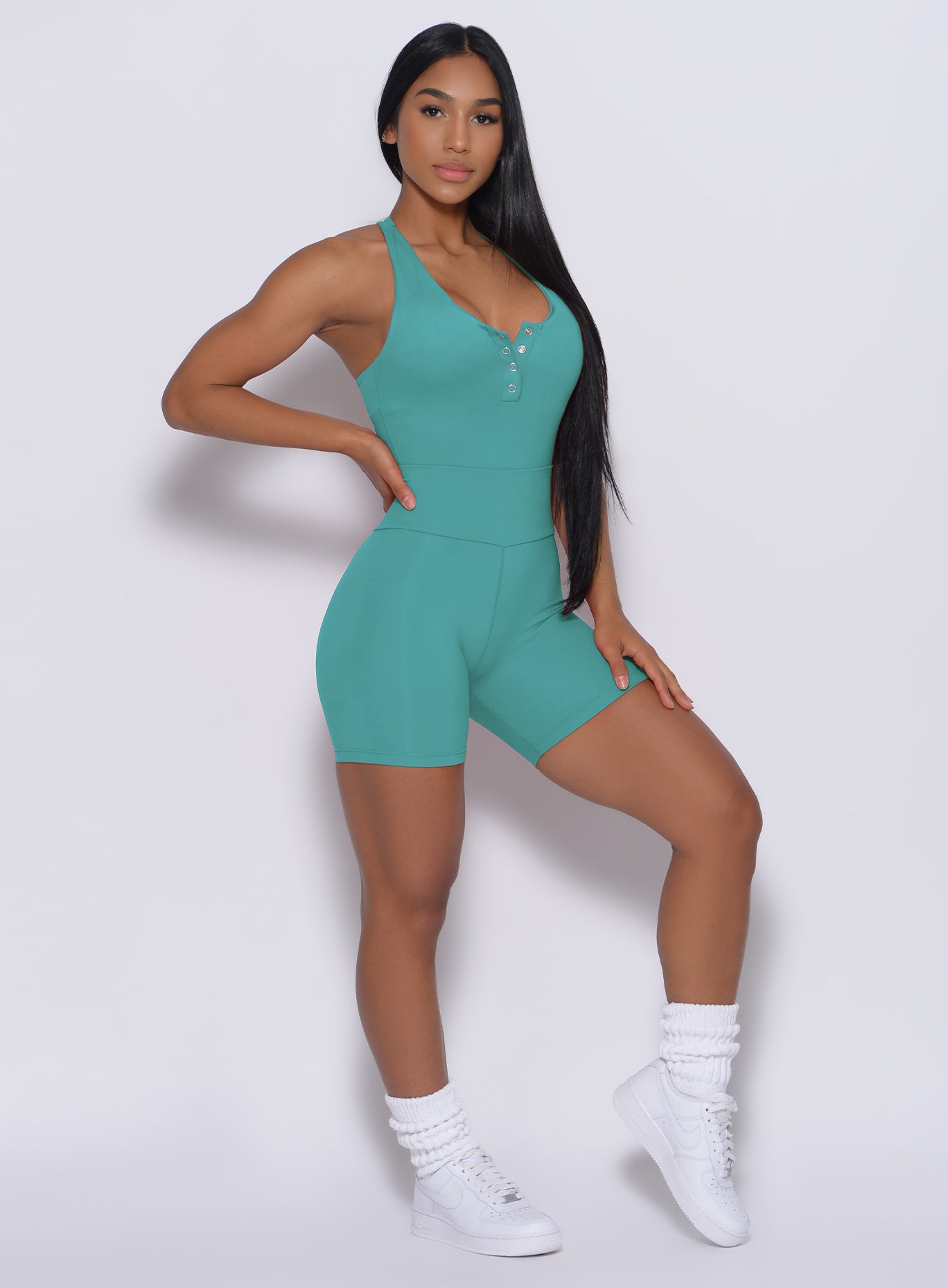 A picture of a model facing forward wearing our refined shorts in green tea color and a matching bodysuit 