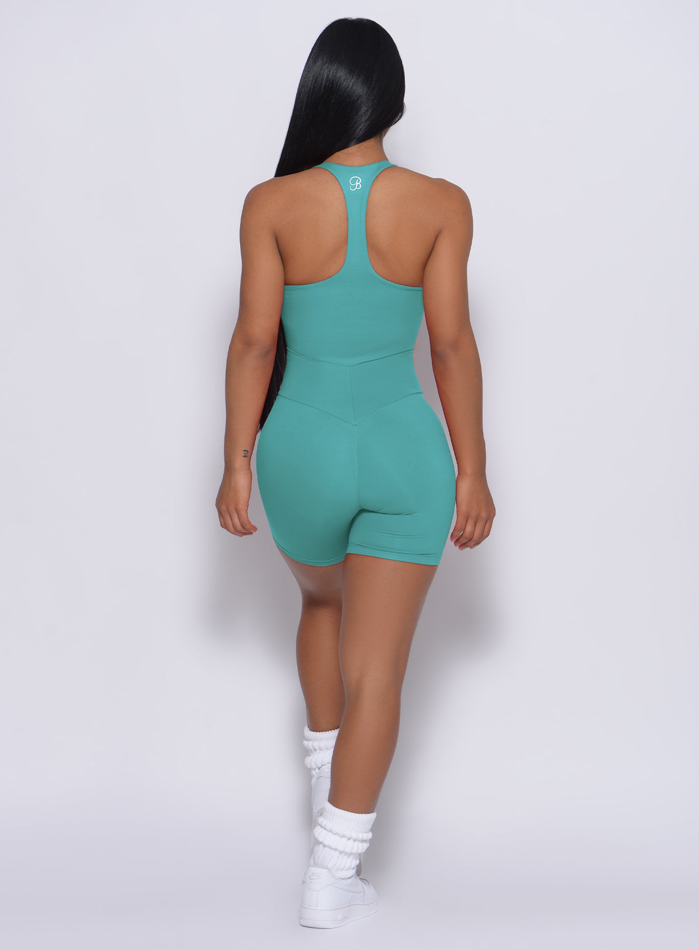 back profile profile view of the model wearing our refined shorts in green tea color and a matching bodysuit