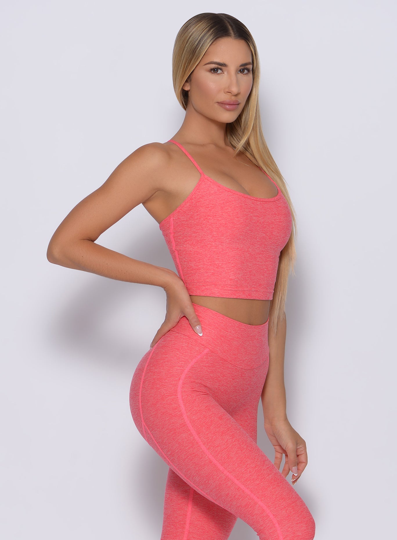 Right side view of a model angled right wearing our relax sports bra in papaya color and a matching leggings