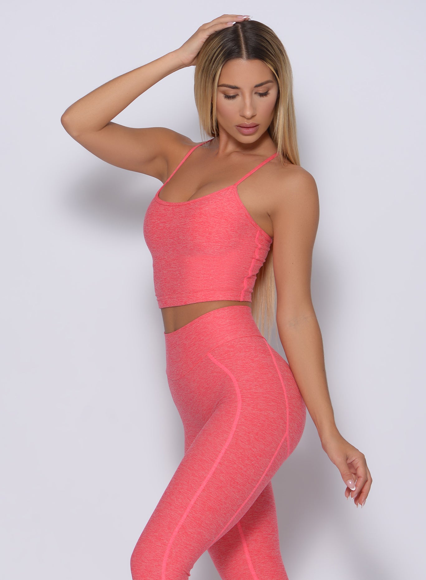 Left side view of a model angled left wearing our relax sports bra in papaya color and a matching leggings 