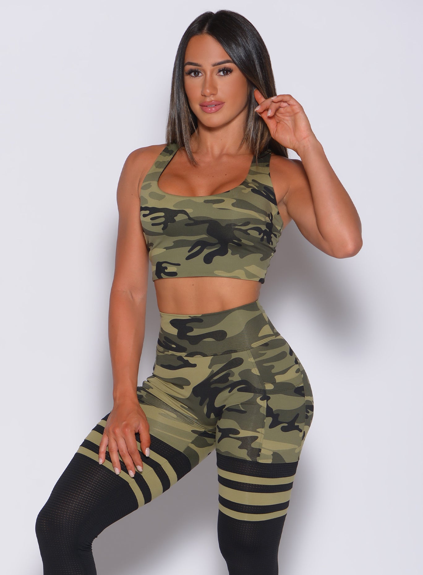 Front profile view of a model wearing our green camo reversible tank bra and a matching leggings