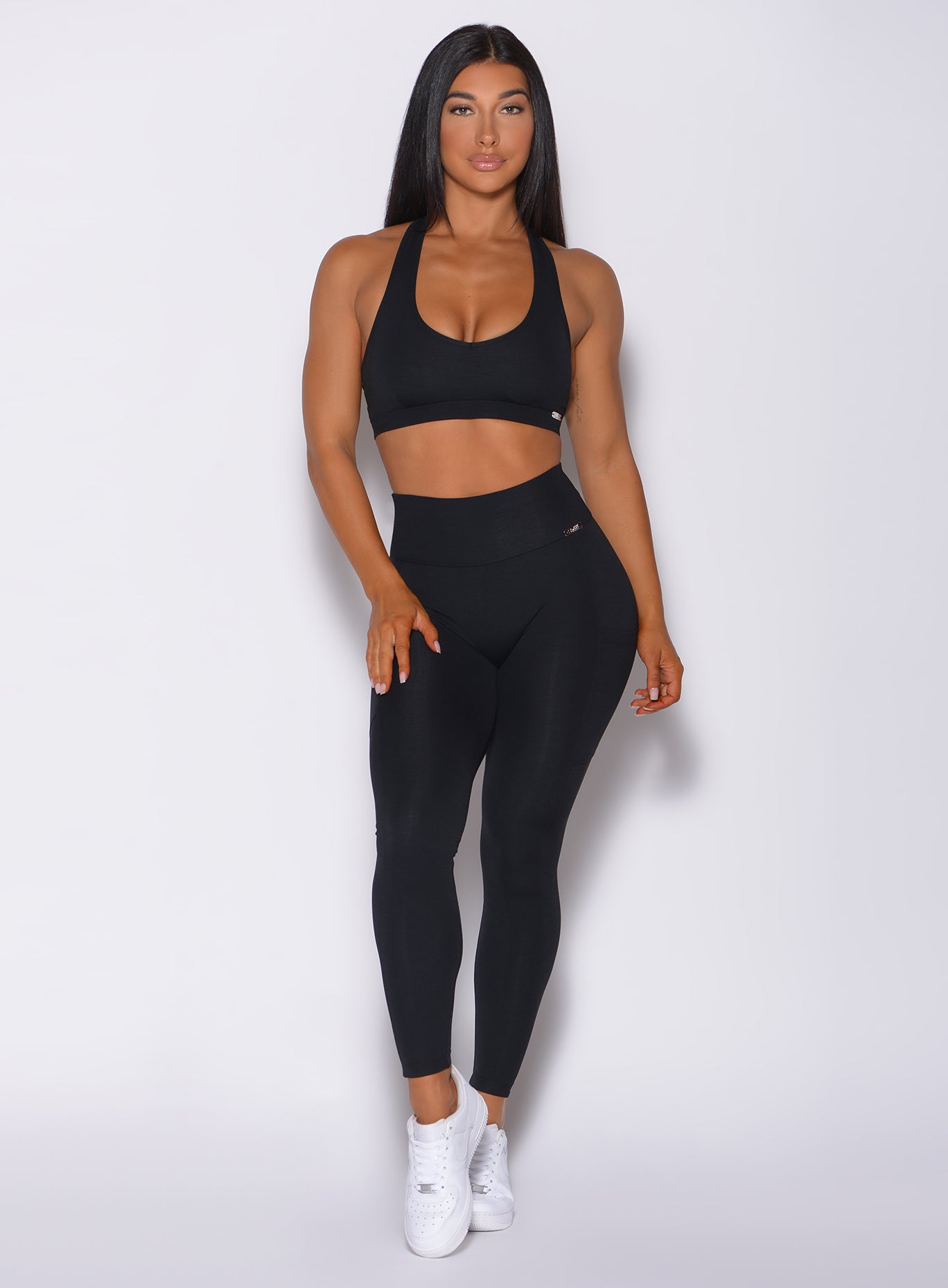 Front profile view of a model in our black pocket rib leggings and a matching bra 