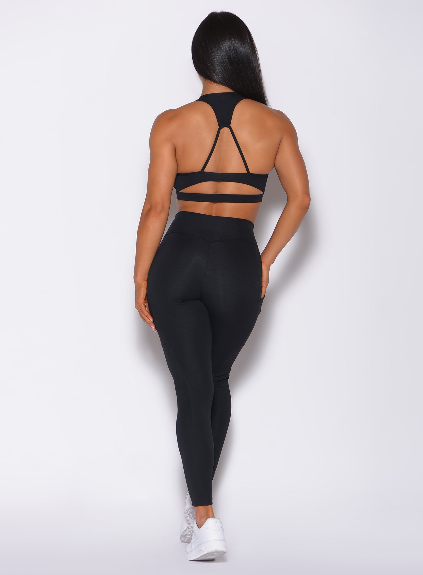 back profile view of a model in our black pocket rib leggings and a matching bra