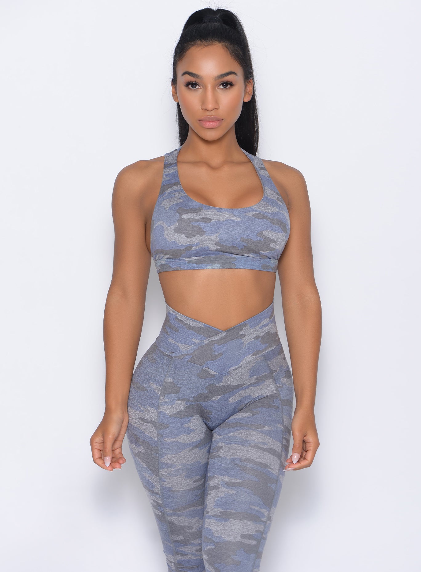Front profile view of the model in our rockstar sports bra in silver color and a matching leggingsb