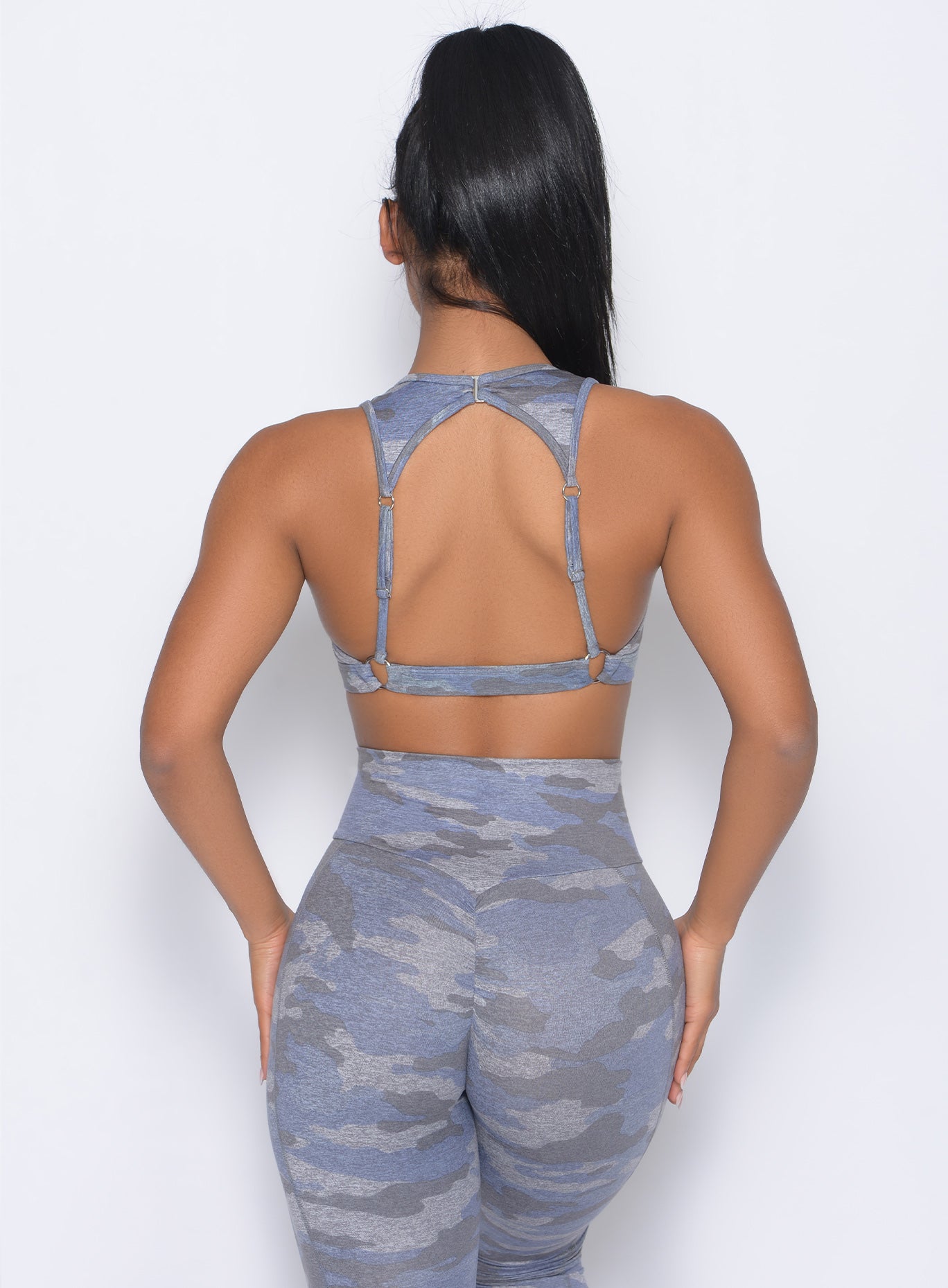 back view of the model in our rockstar sports bra in silver color  and a matching leggings 