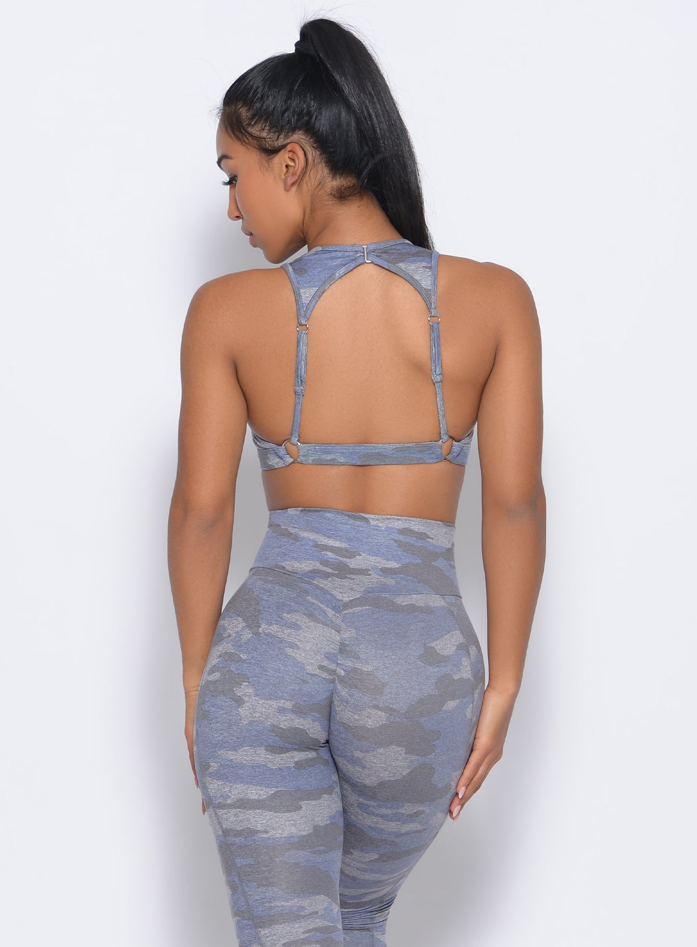 Back profile view of the model in our rockstar sports bra in silver color and a matching leggings