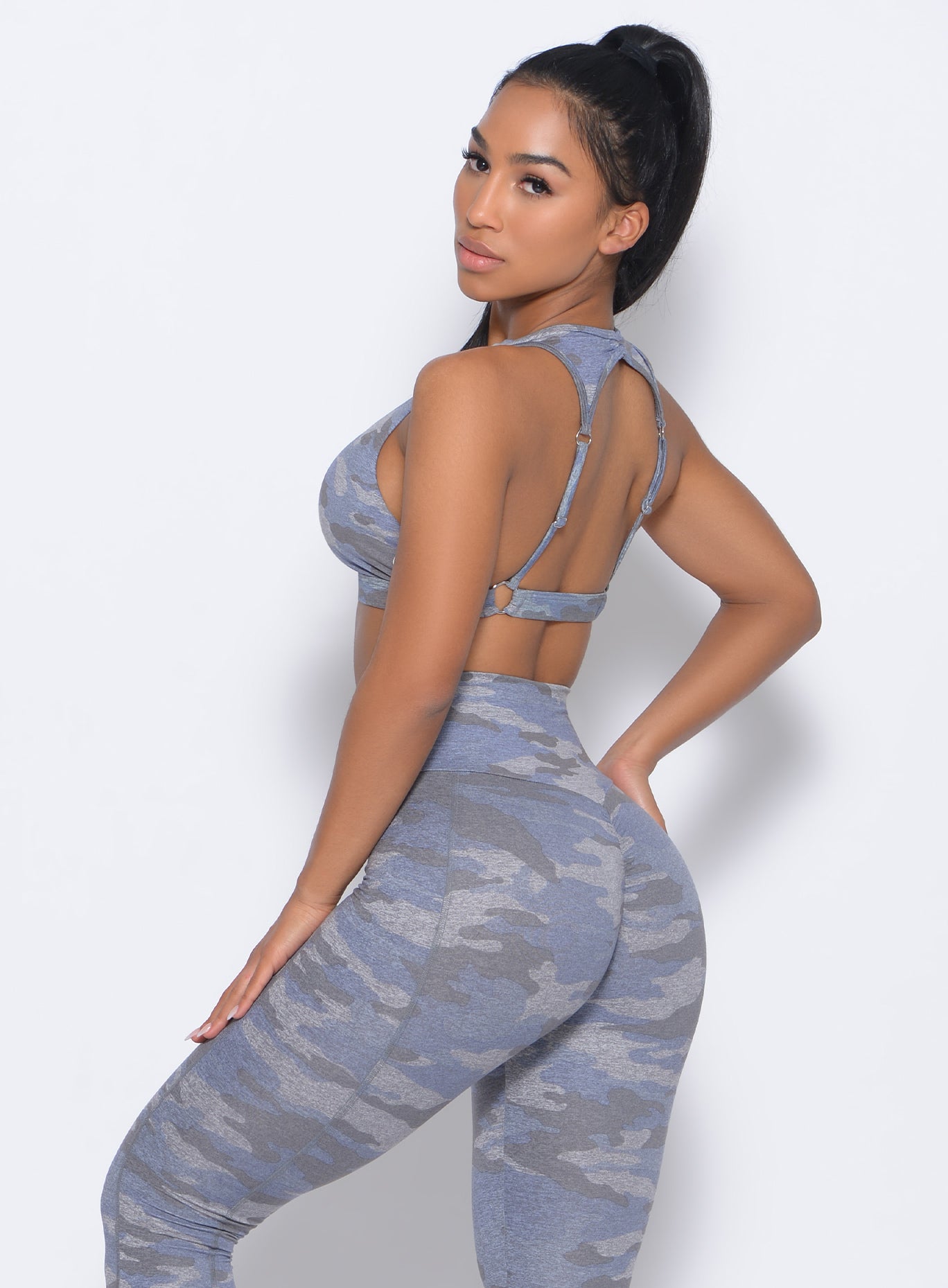 Left side view of the model facing to her left wearing  our rockstar sports bra in silver color and a matching leggings