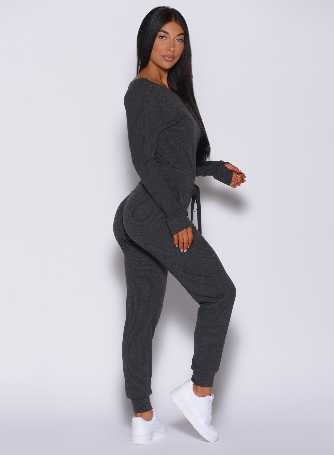 Right side profile view of a model facing to her right wearing our Rib Jumpsuit in charcoal color 