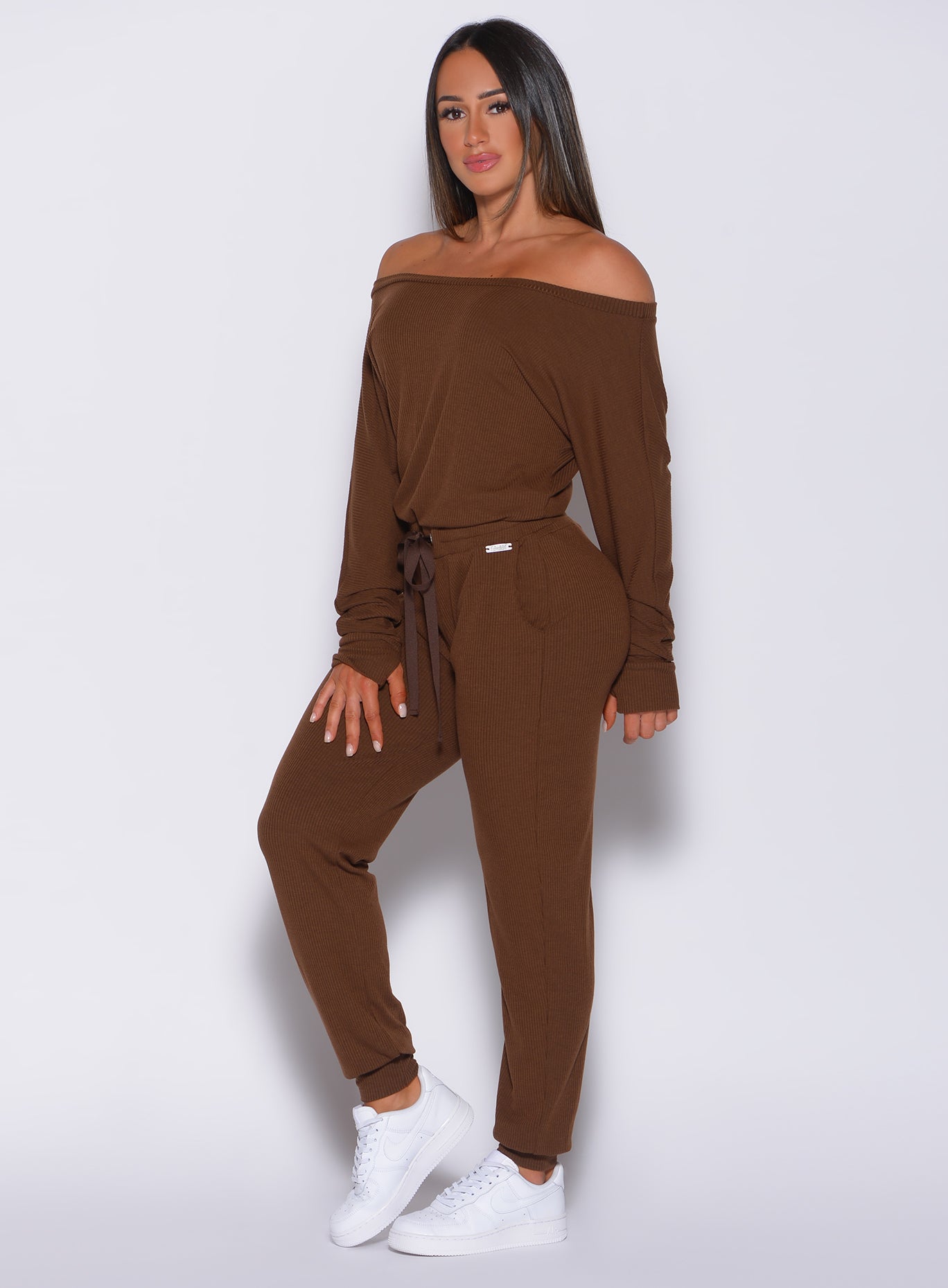 Front profile view of a model facing forward wearing our rib jumpsuit in expresso color