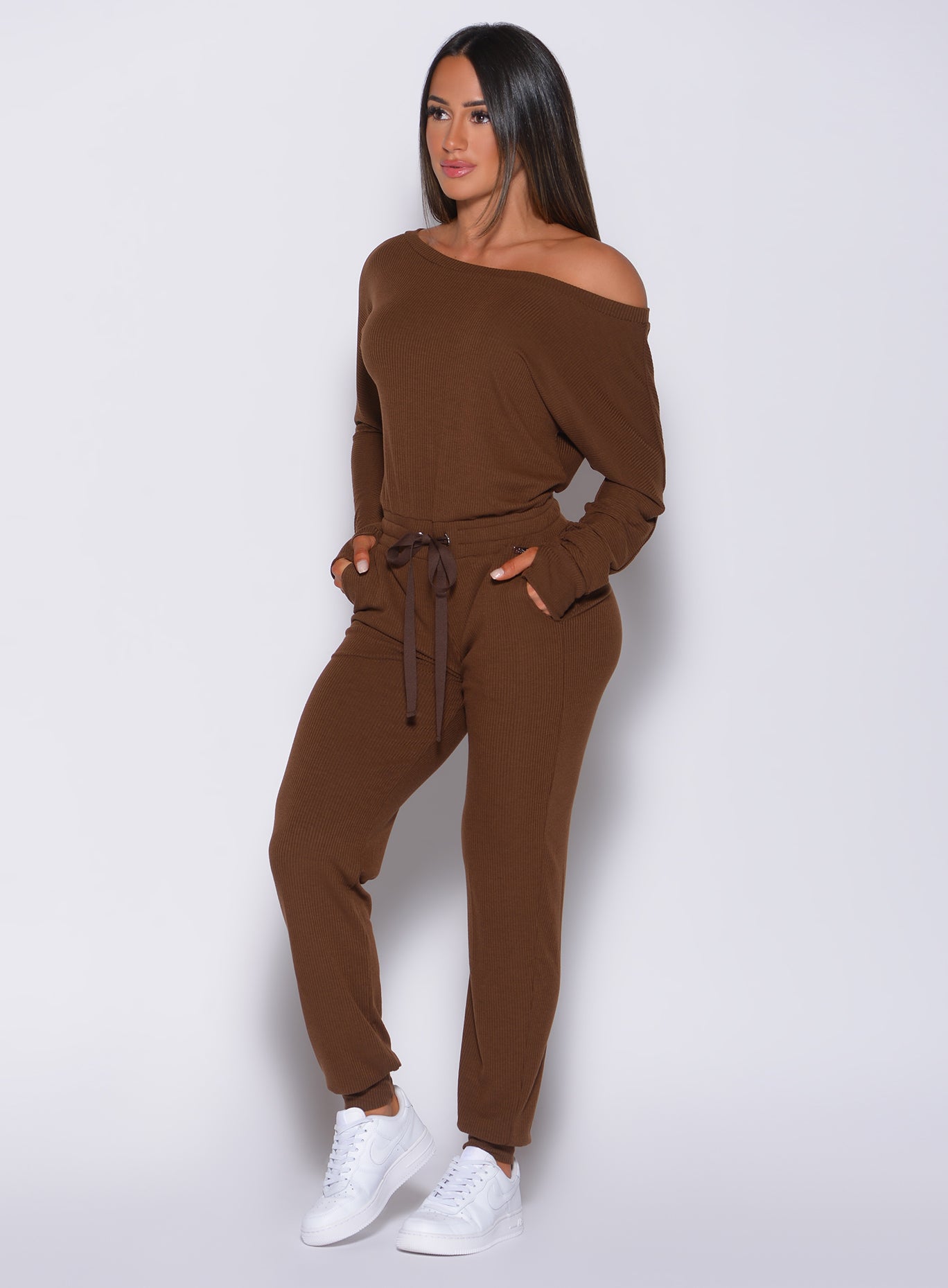 Front profile view of a model with her hands in pocket wearing our rib jumpsuit in expresso color 
