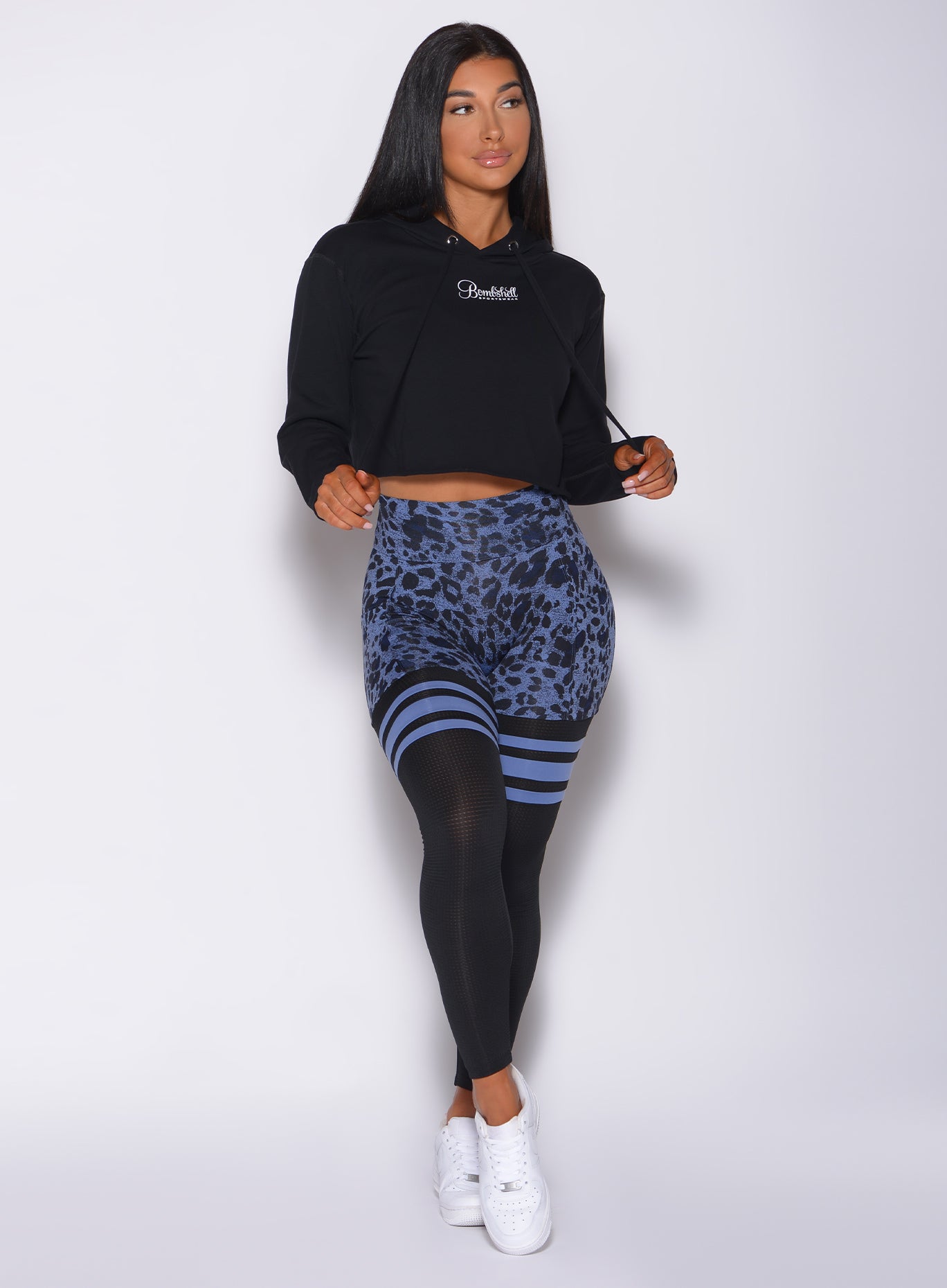 Front profile view of a model in our scrunch thigh high in blue leopard print and a black hoodie 
