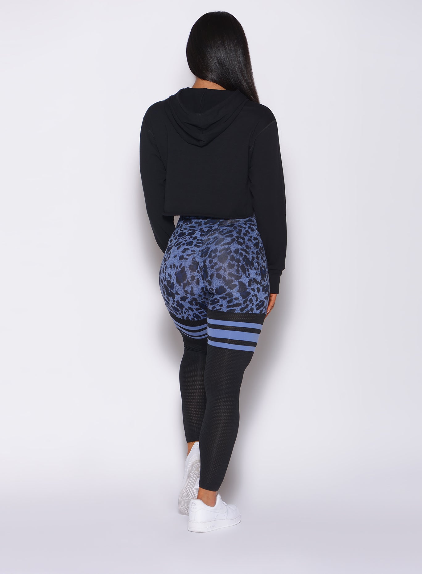 Back profile view of a model in our scrunch thigh high in blue leopard print and a black hoodie 