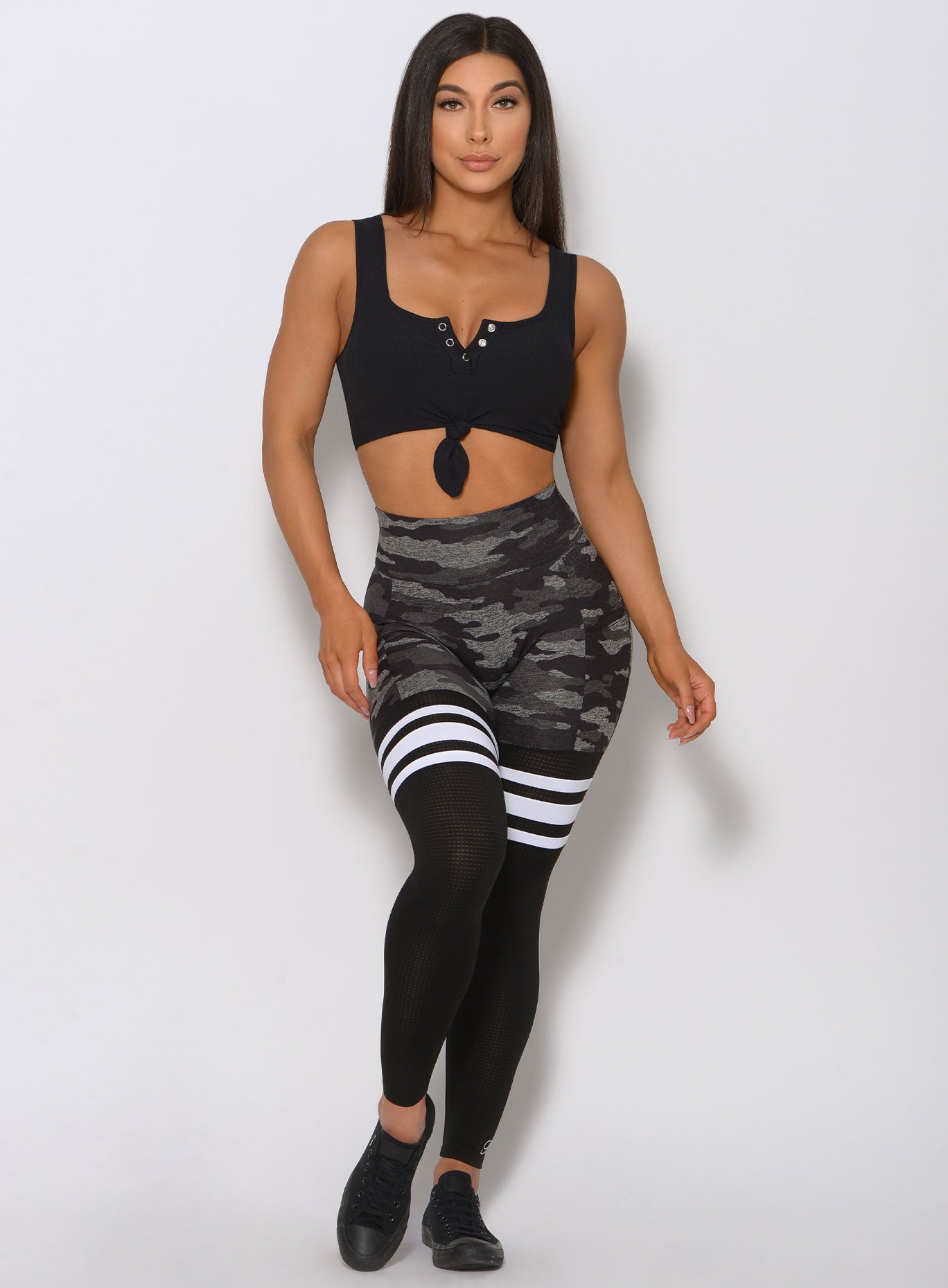 Front view of the model wearing our black henley tank with a camo print leggings