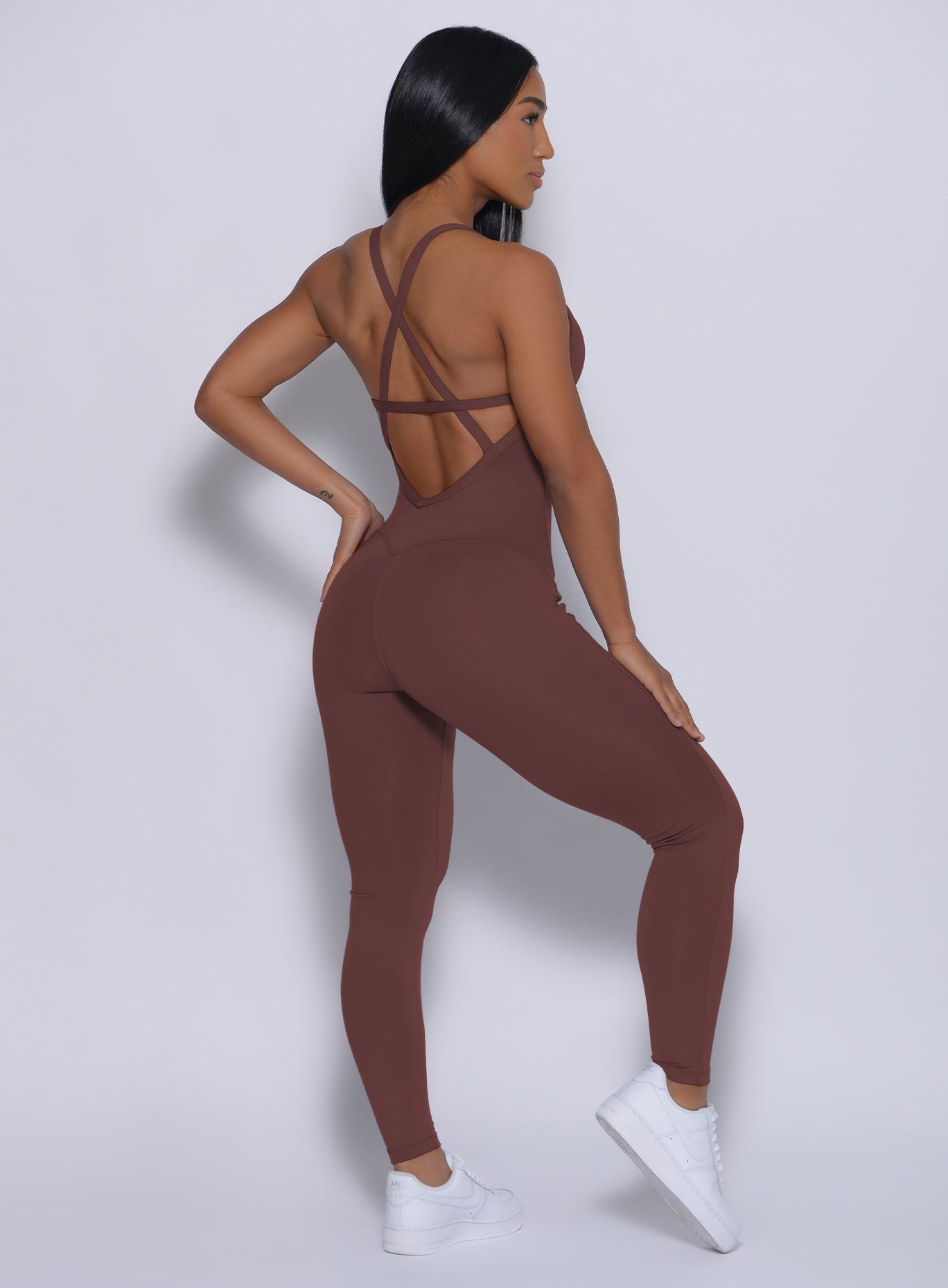Back profile view of a model wearing our sculpted bodysuit in chocolate color
