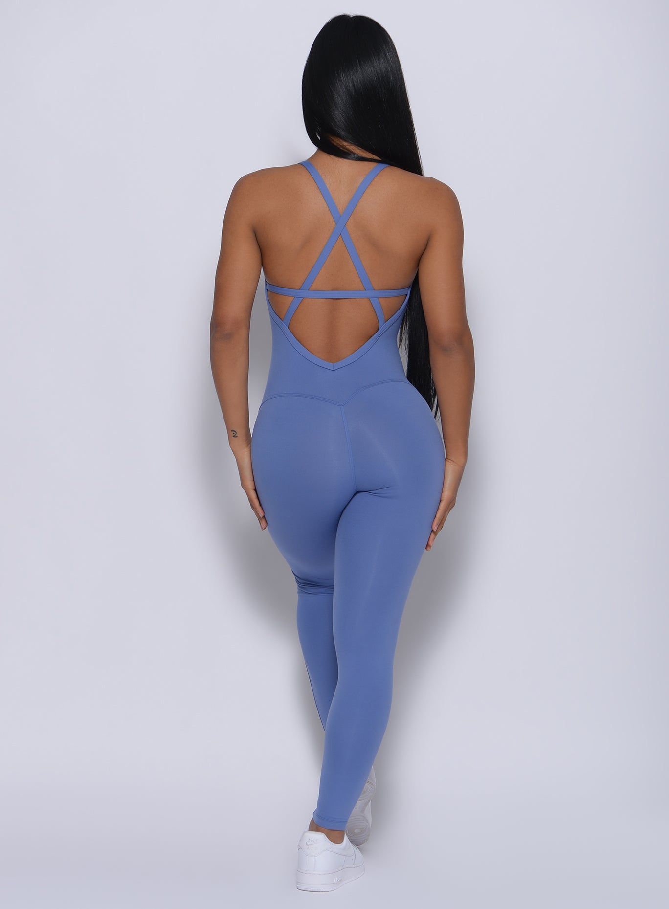 Back profile picture of a model in our sculpted bodysuit in denim blue color