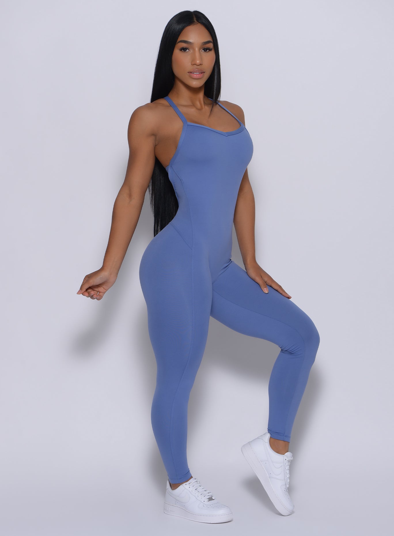 Right side profile view of a model angled right wearing our sculpted bodysuit in denim blue color