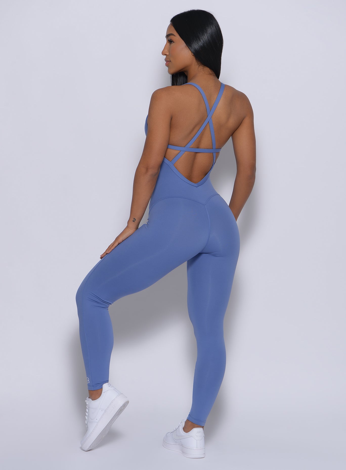Back profile view of a model in our sculpted bodysuit in denim blue color
