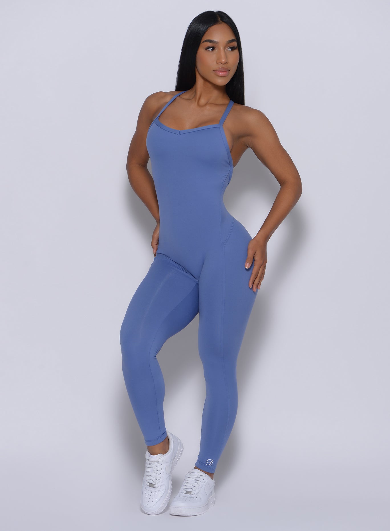 Front profile picture of a model with her hands on waist wearing our sculpted bodysuit in denim blue color 