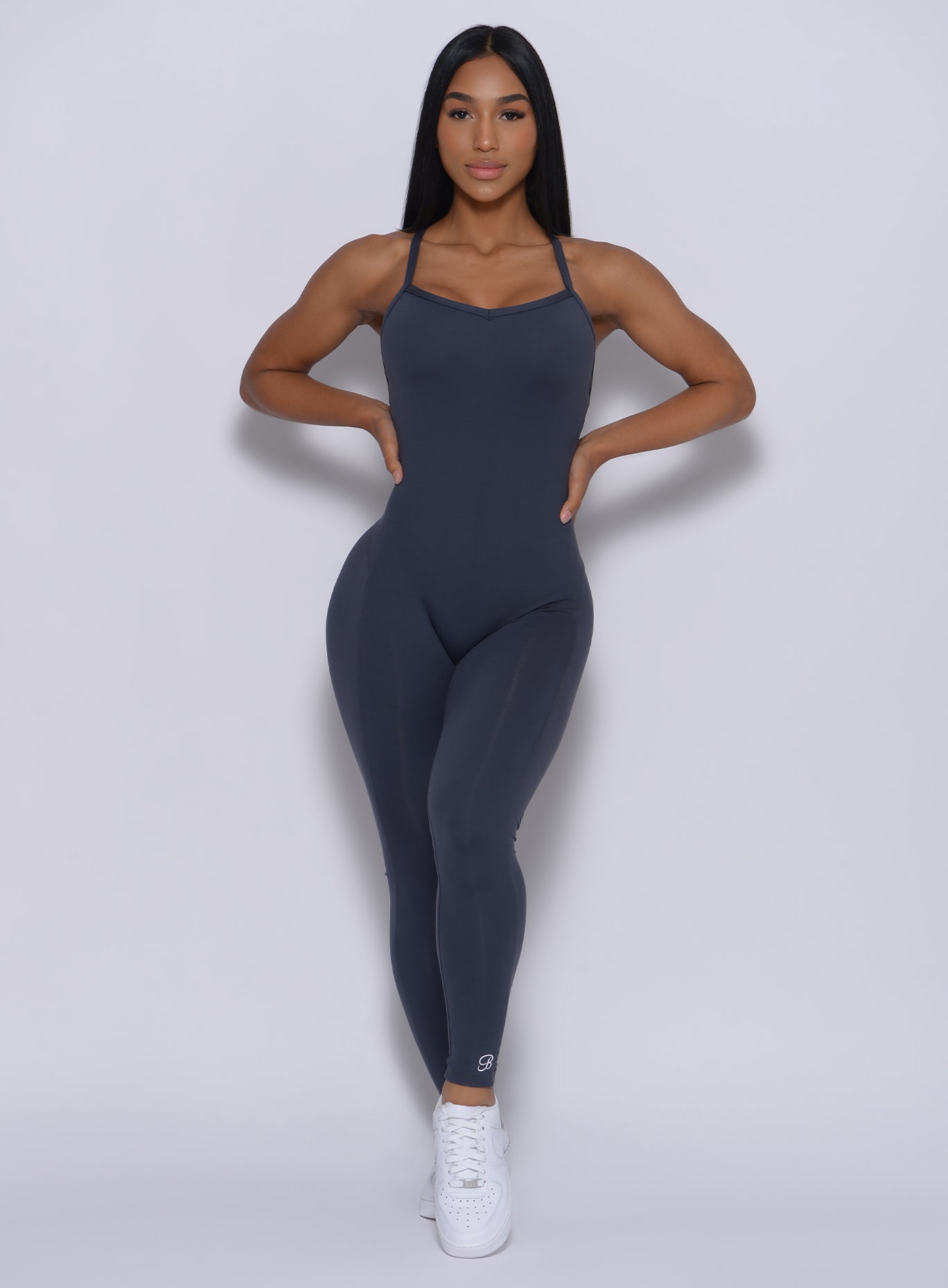 Front profile  profile view of a model with her hands on waist wearing our sculpted bodysuit in summit gray color