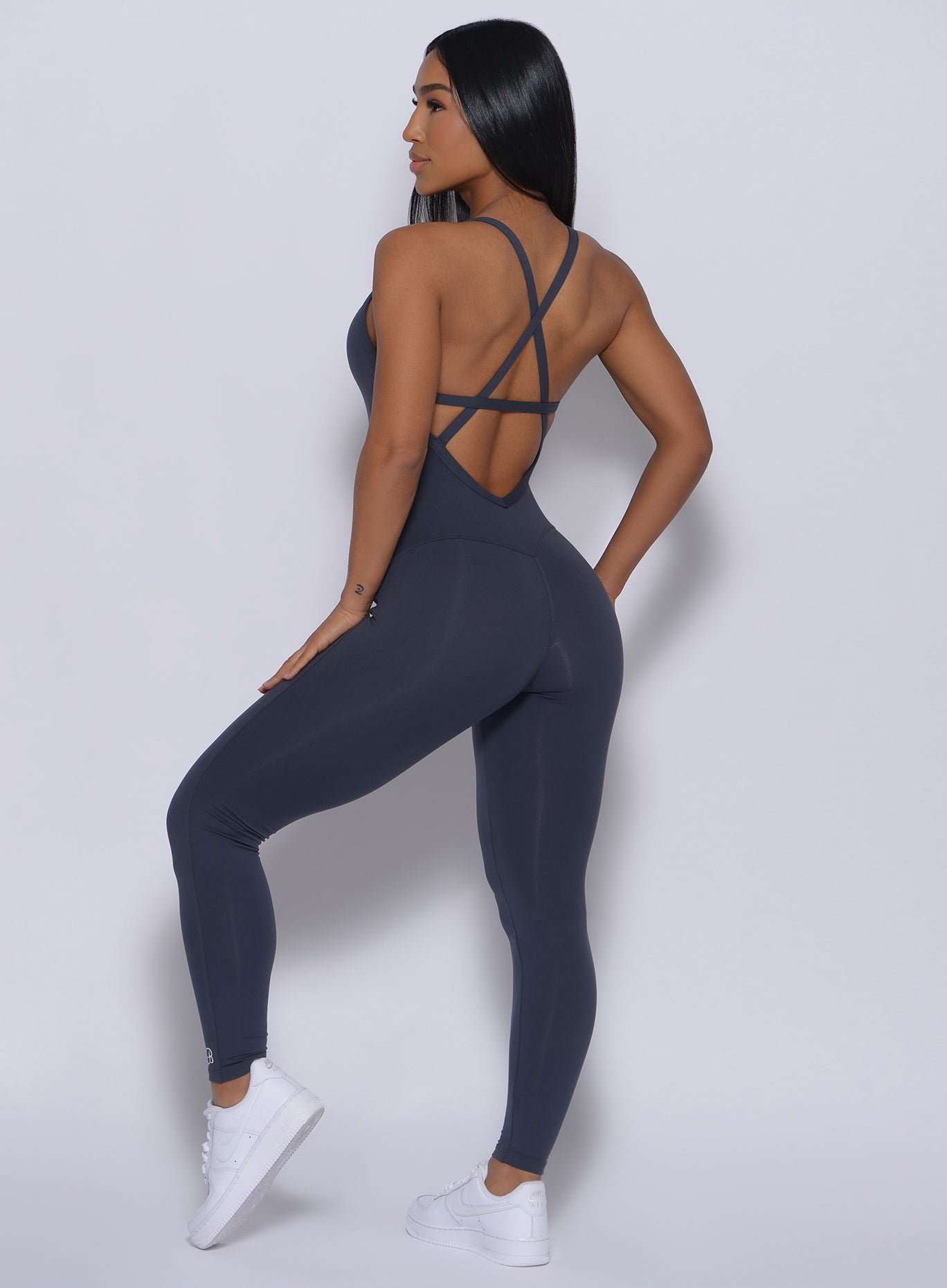 Back profile view of a model angled right wearing our sculpted bodysuit in summit gray color