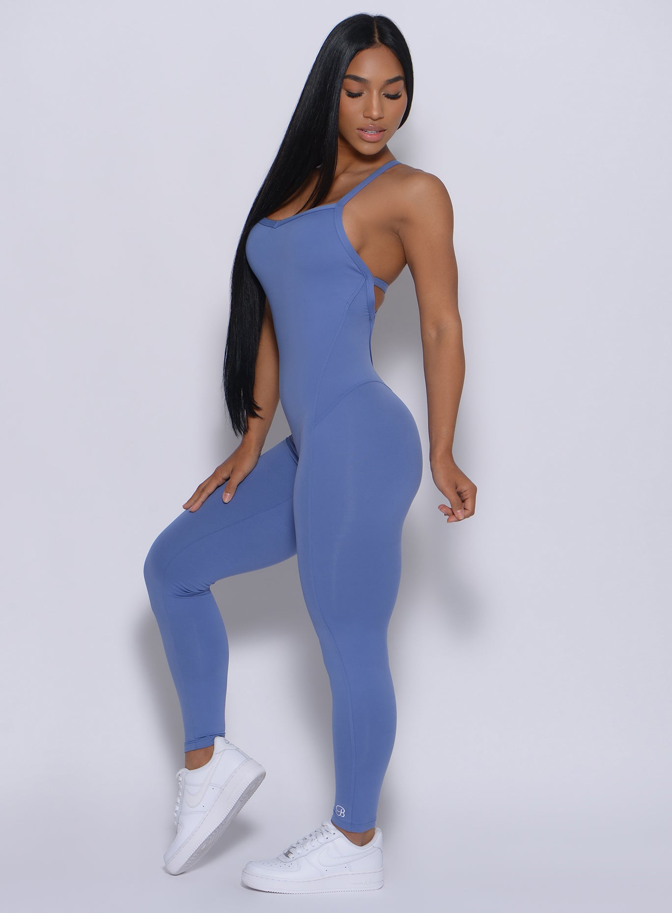 Left side profile view of a model angled left wearing our sculpted bodysuit in denim blue color