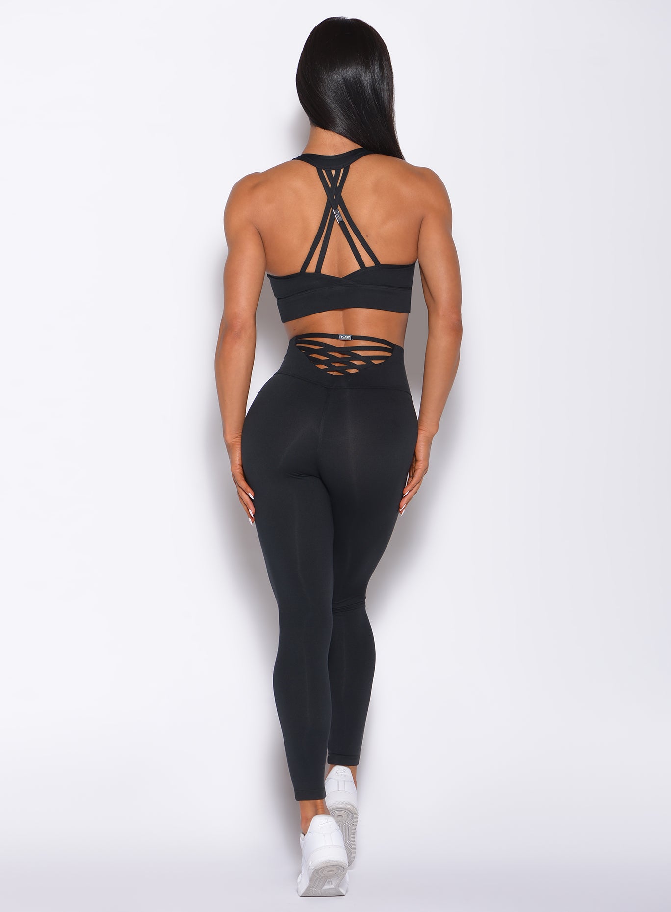 Back profile view of a model in our new black sexy back leggings and a matching sports bra 
