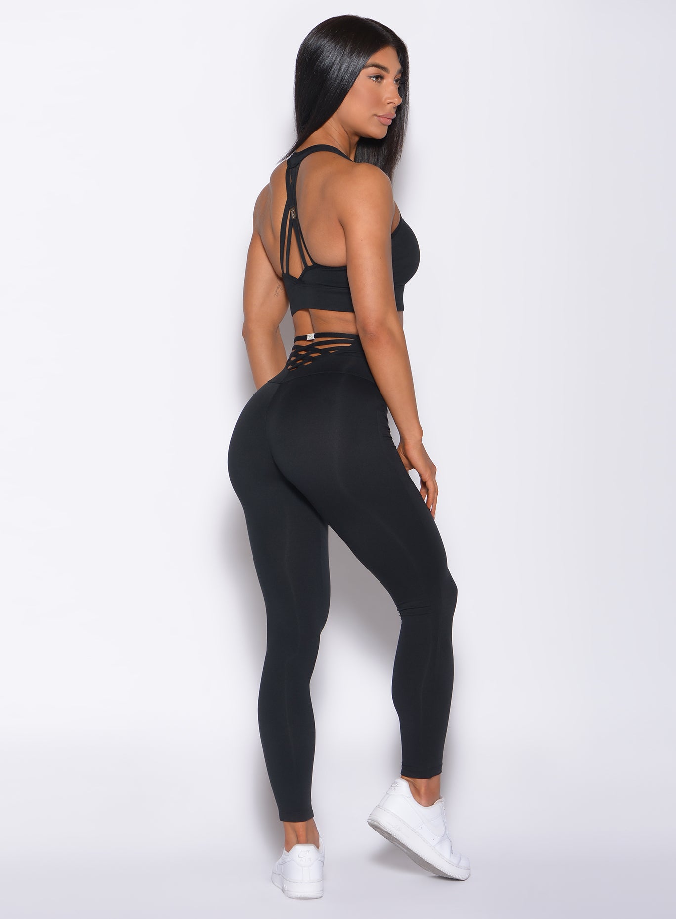 Right side profile view of a model in our black sexy back leggings and a matching sports bra 