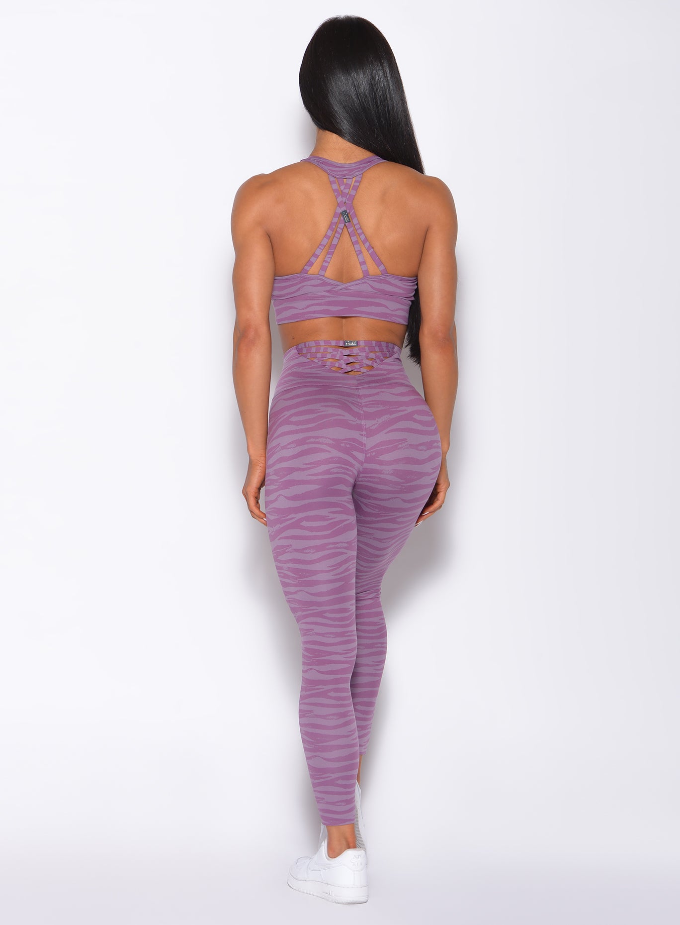 Back profile view of a model wearing our sexy back legging in orchid purple color and a matching bra
