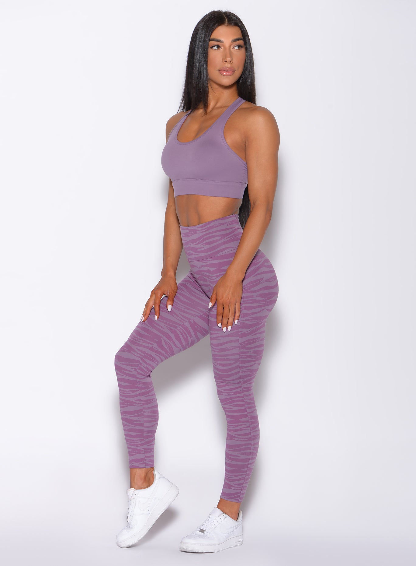 Picture of a model captured in a left-side profile, angled slightly to her left while flaunting our alluring orchid purple sexy back leggings and matching bra.