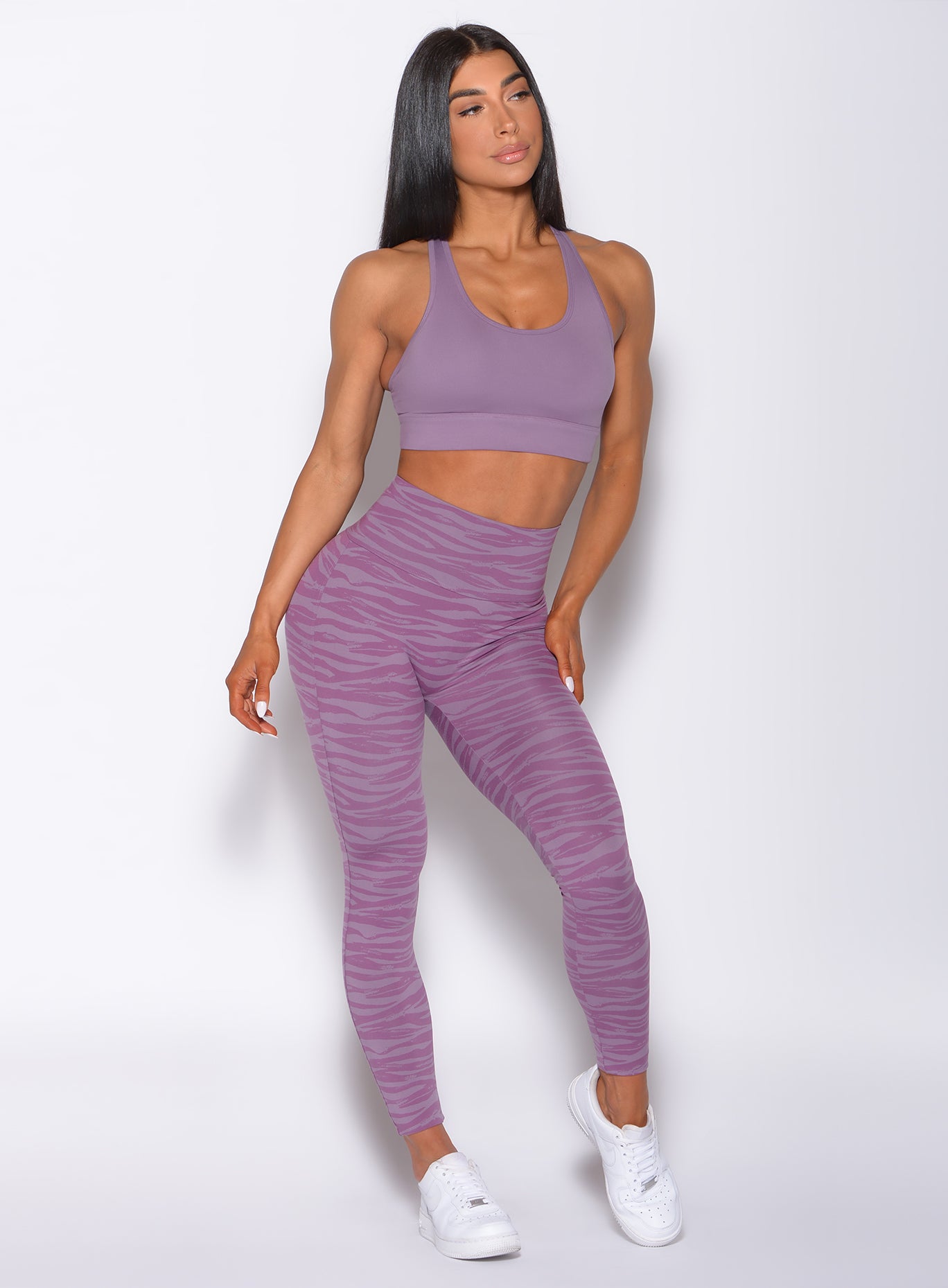 Front profile view of a model facing to her left wearing our sexy back legging in orchid purple color and a matching bra