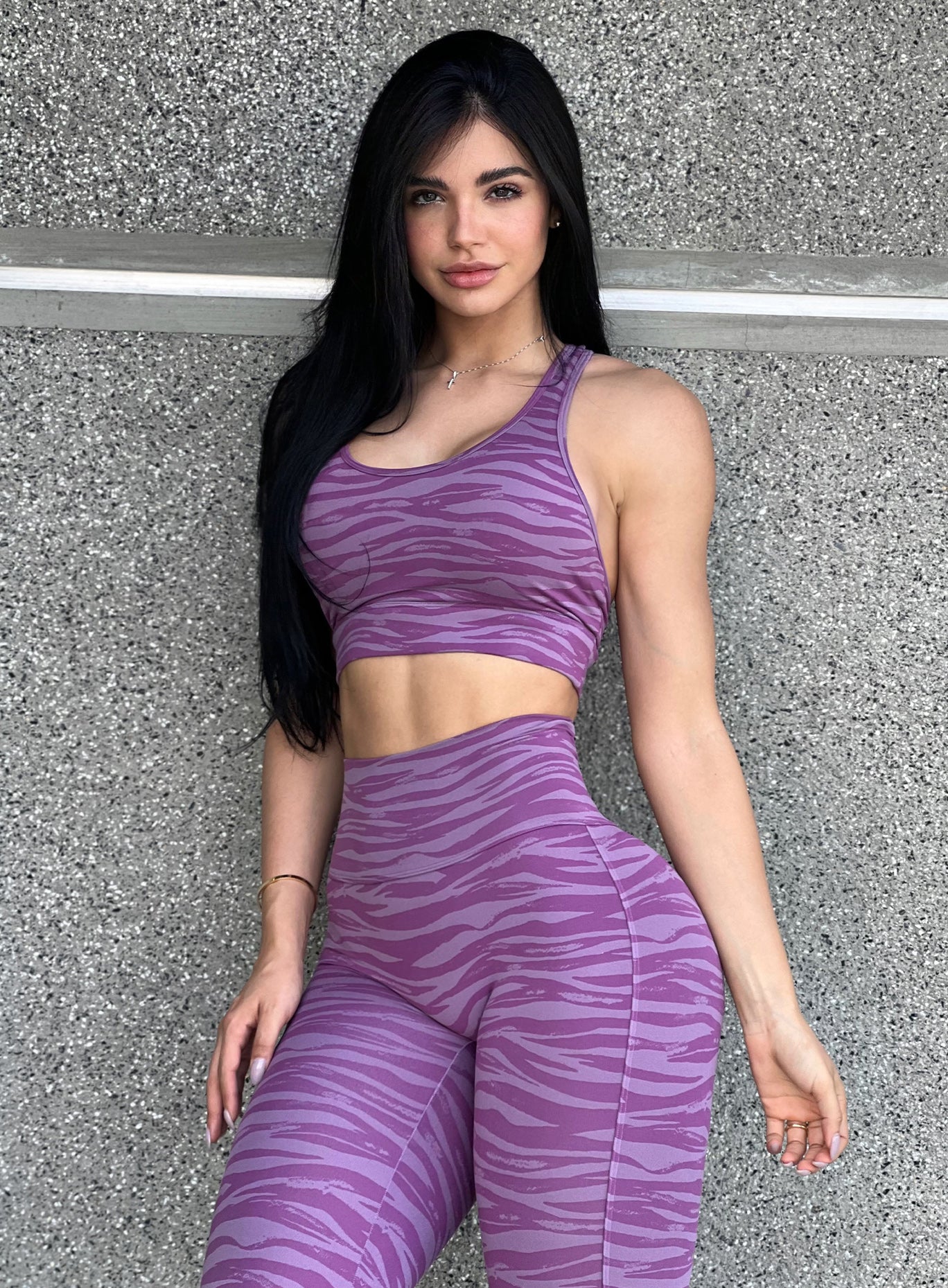 Front profile view of a model in our tiger printed rival sports bra in orchid purple color and a matching sexy back leggings 
