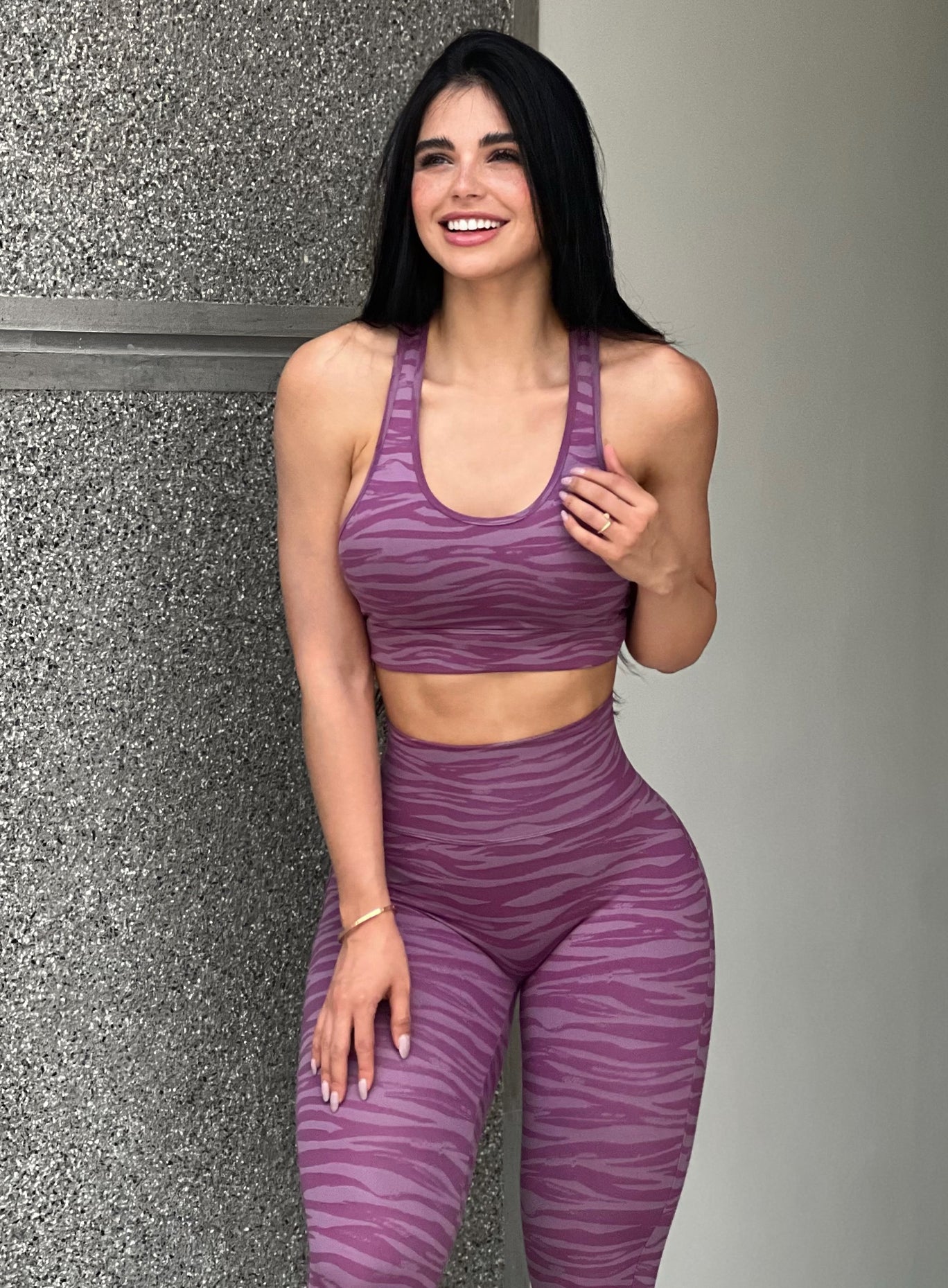 Front  profile view of a model wearing our tiger printed rival sports bra in orchid purple color and a matching sexy back leggings
